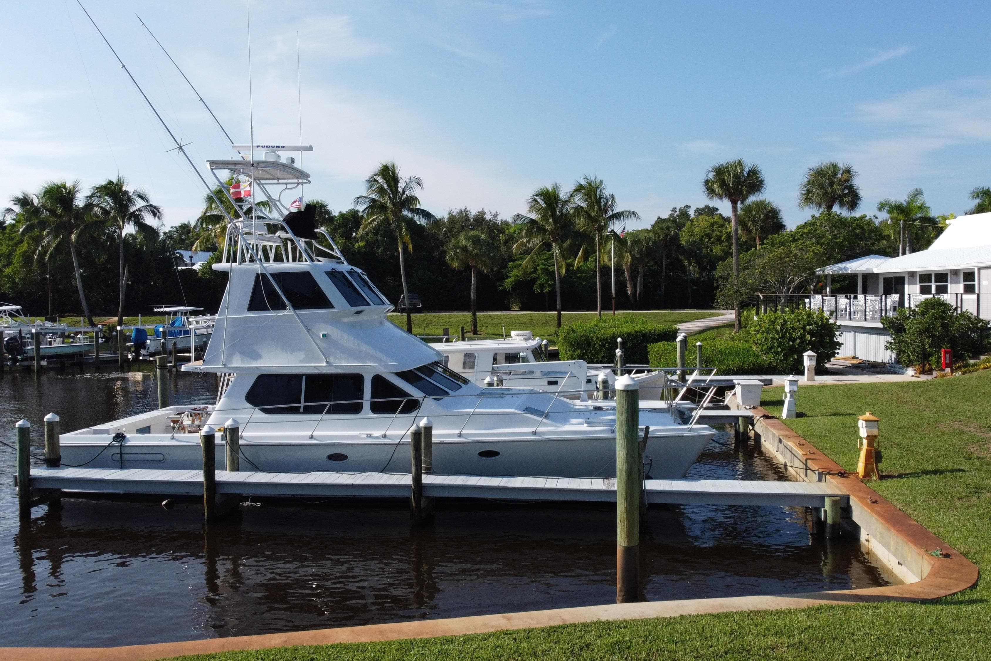 Voyager 44 yacht docked at marina, surrounded by palm trees, sunny day, 2000 model.