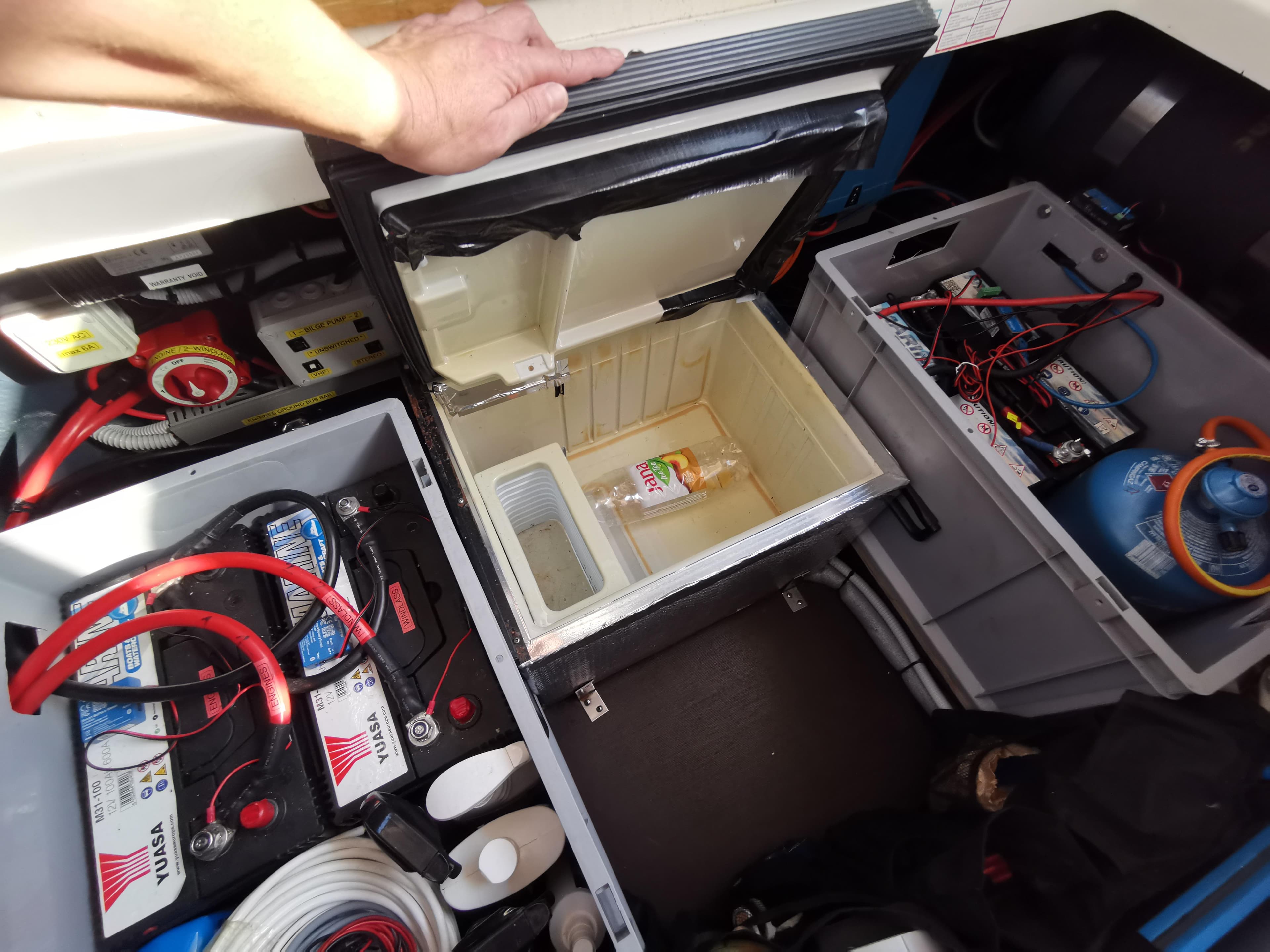 Open storage compartment in 1999 Cranchi CSL 28 boat, showing batteries and a small fridge.