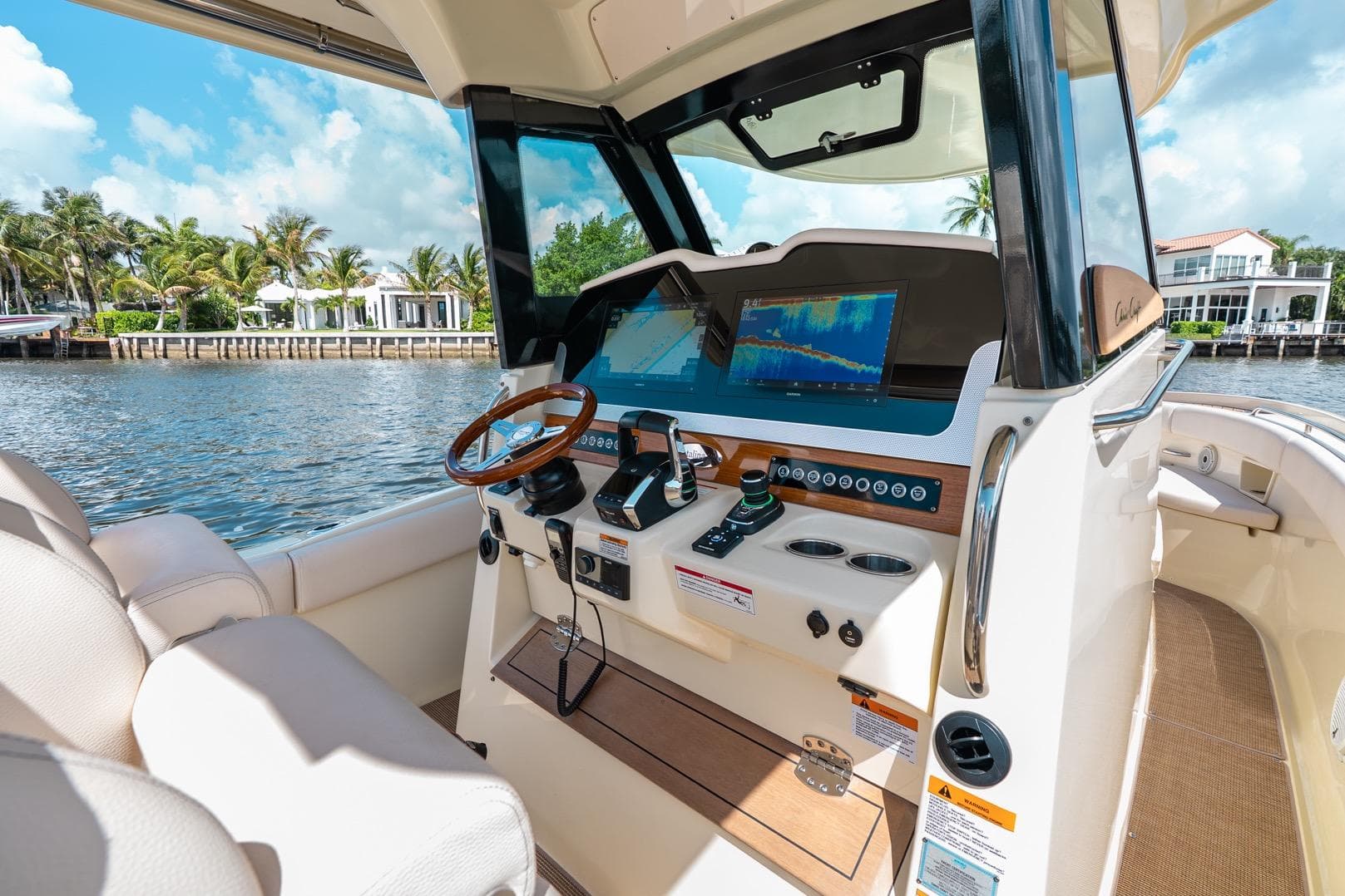 2024 Chris-Craft Catalina 30 helm with modern controls, luxurious seating, and scenic waterfront view.