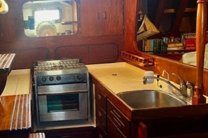 1974 Spencer Yachts 1330 kitchen with stove, sink, and wooden cabinetry.