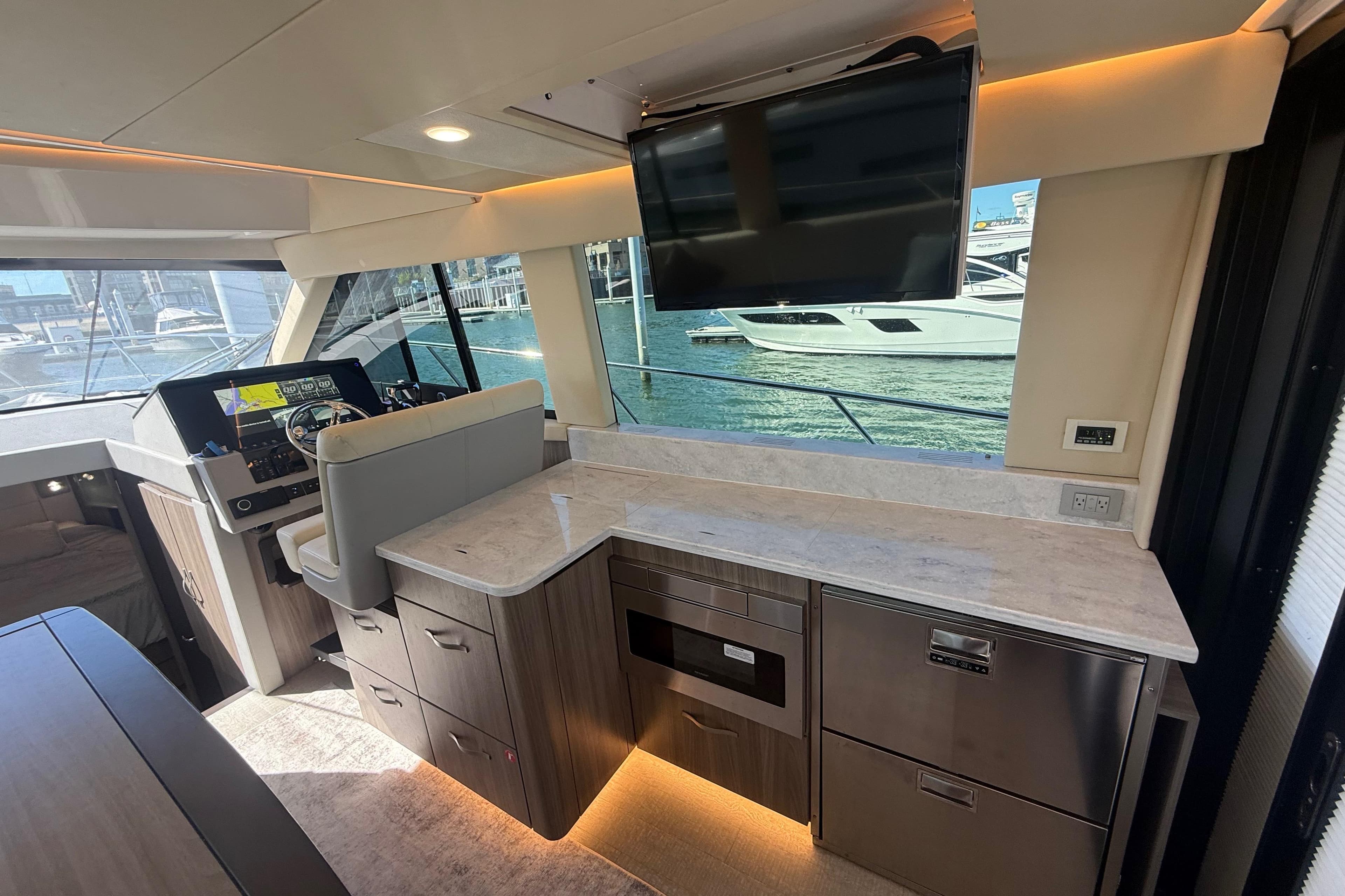 Luxurious interior of 2022 Regal 42 FXO yacht with modern helm and galley area.