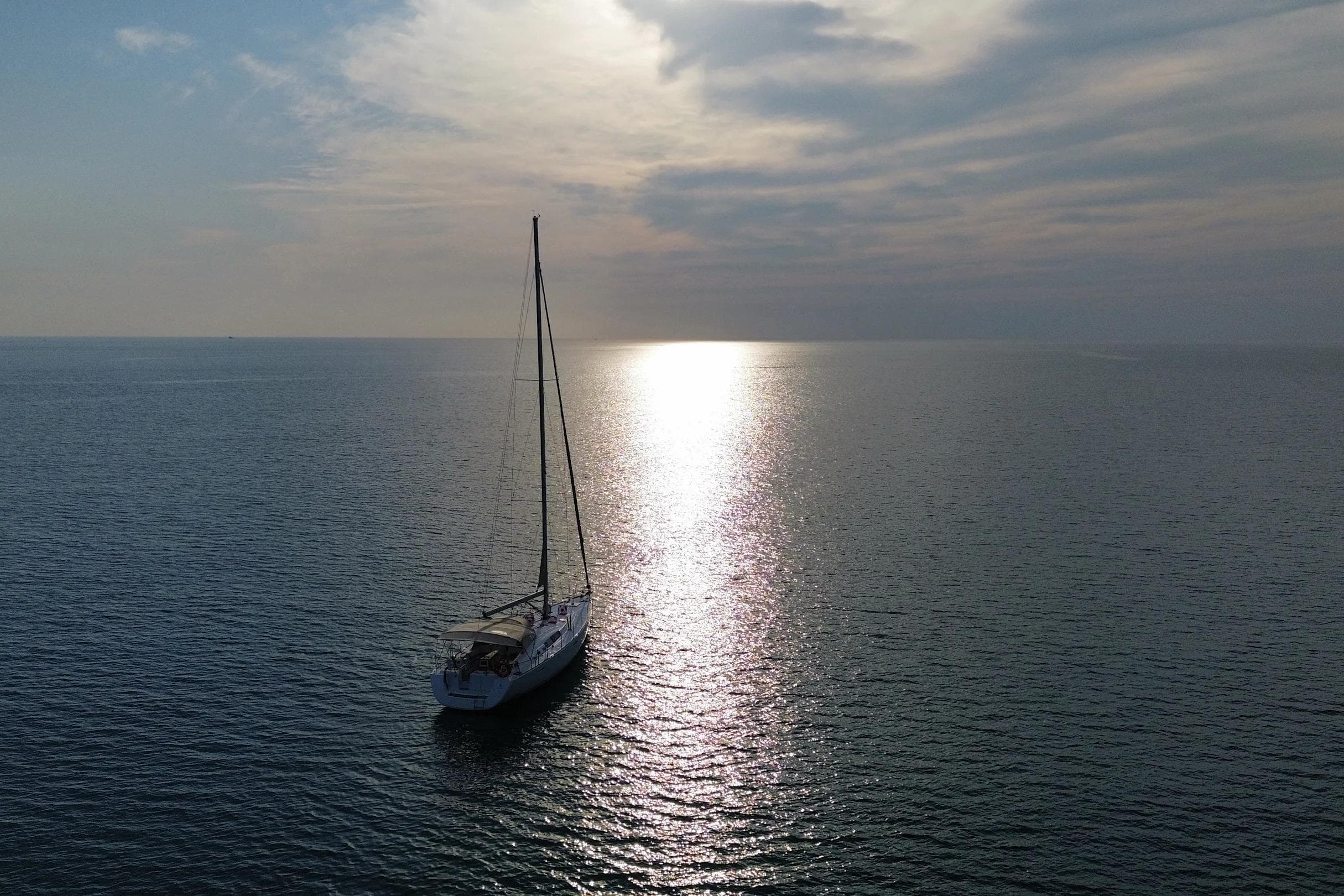 Sailboat Beneteau Oceanis 54, 2013 model, on calm sea at sunset.