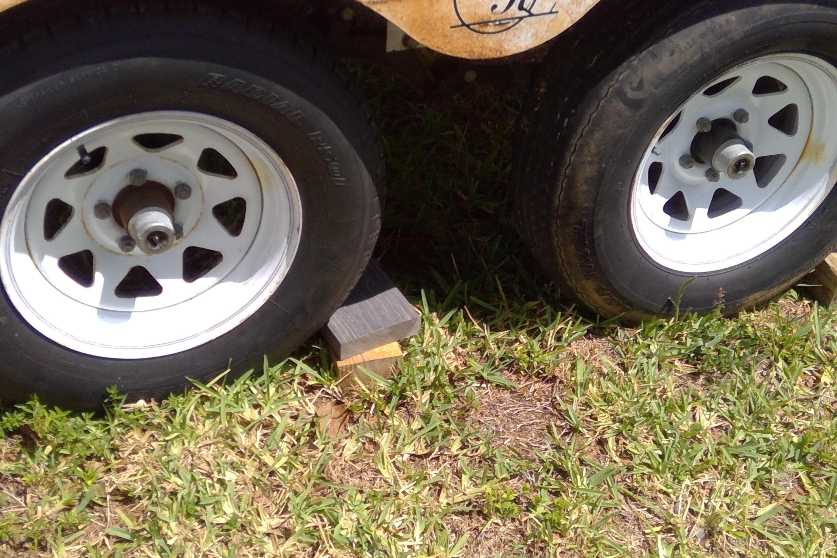 Trailer wheels of a 2007 Tidewater 216 CC Adventure boat on grass.