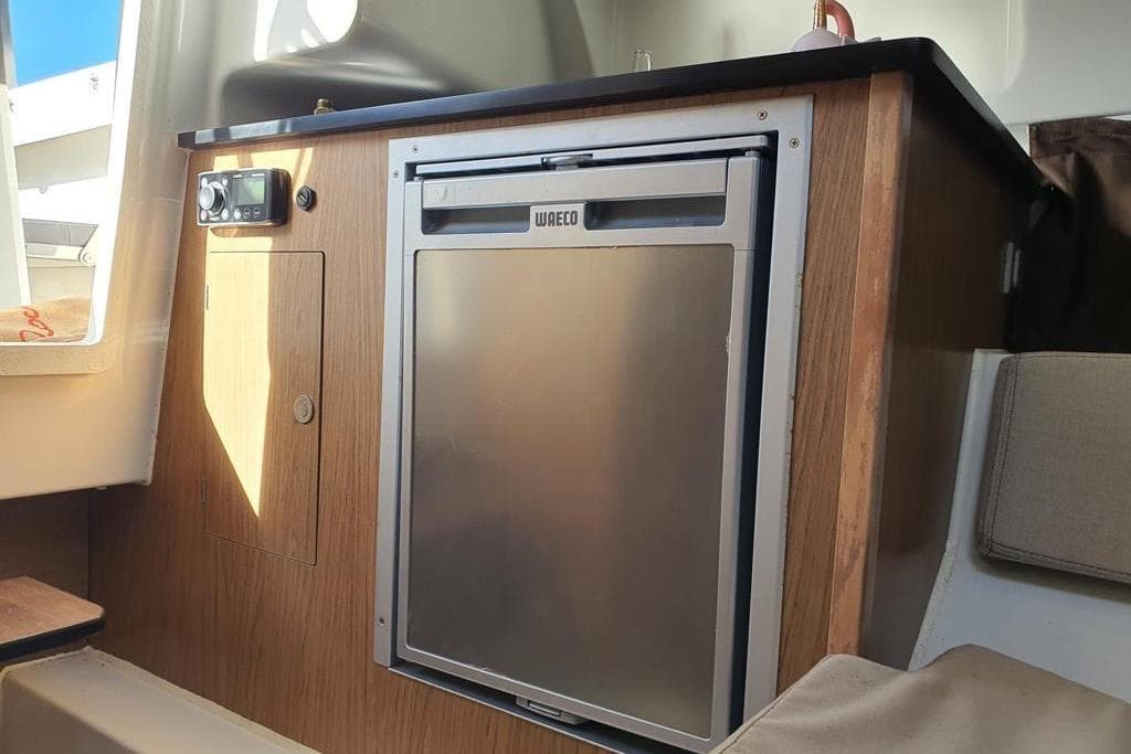 Interior of 2018 Beneteau Flyer 7.7 Sundeck with compact fridge and wooden cabinetry.