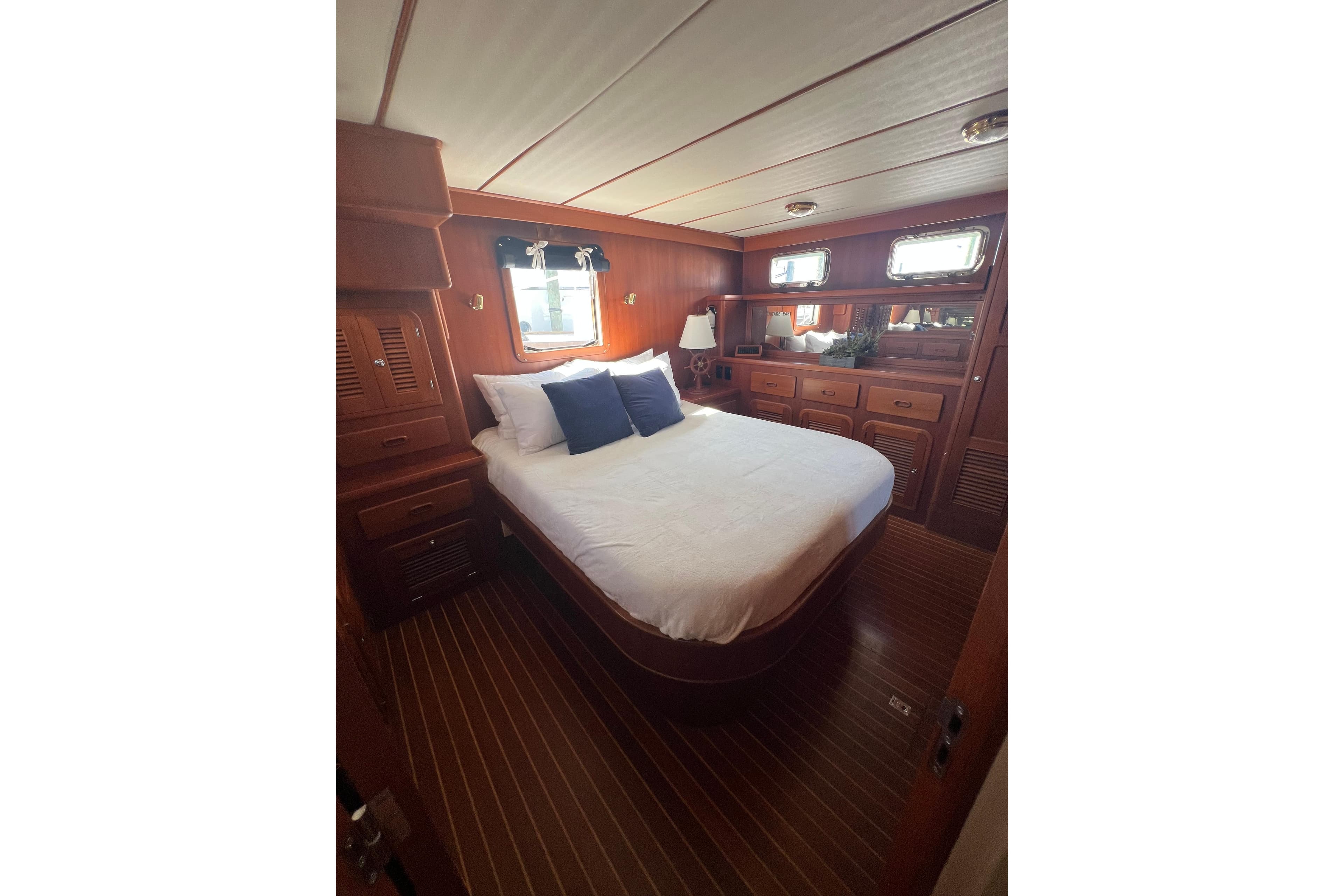 Luxurious 2007 Heritage East Sundeck Trawler bedroom with wood paneling and cozy bedding.