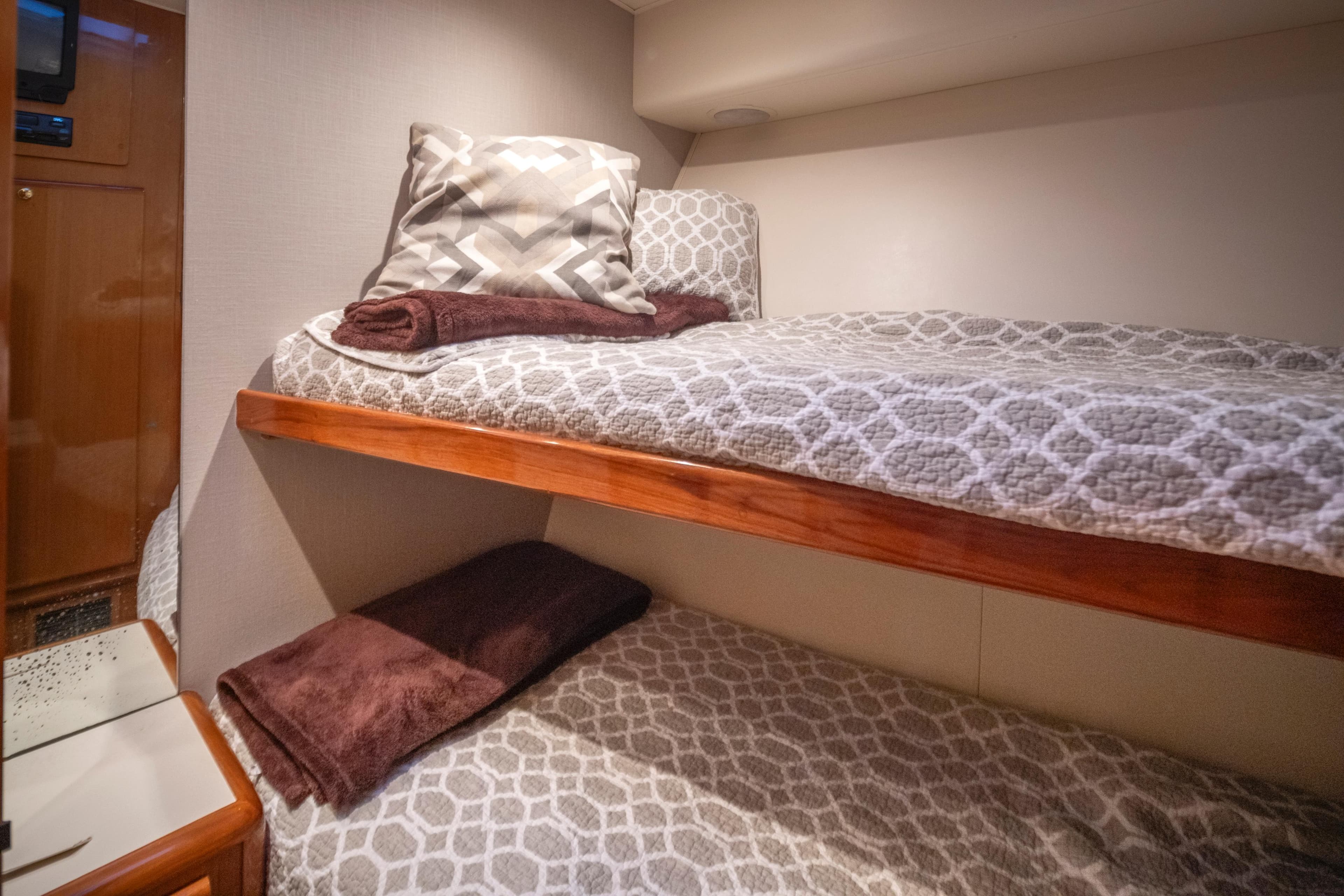 Bunk beds in the 2000 Viking 72 Convertible yacht cabin, featuring patterned bedding and wooden frames.