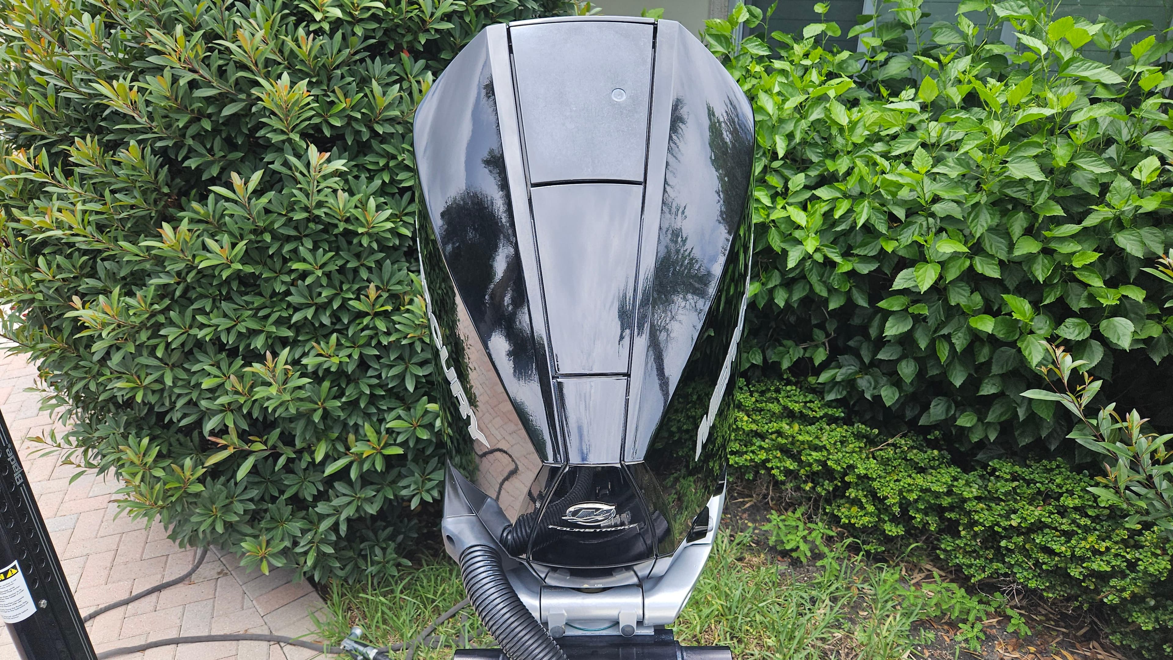 Black outboard motor on a 2021 Scout 231 XS boat, surrounded by lush greenery.