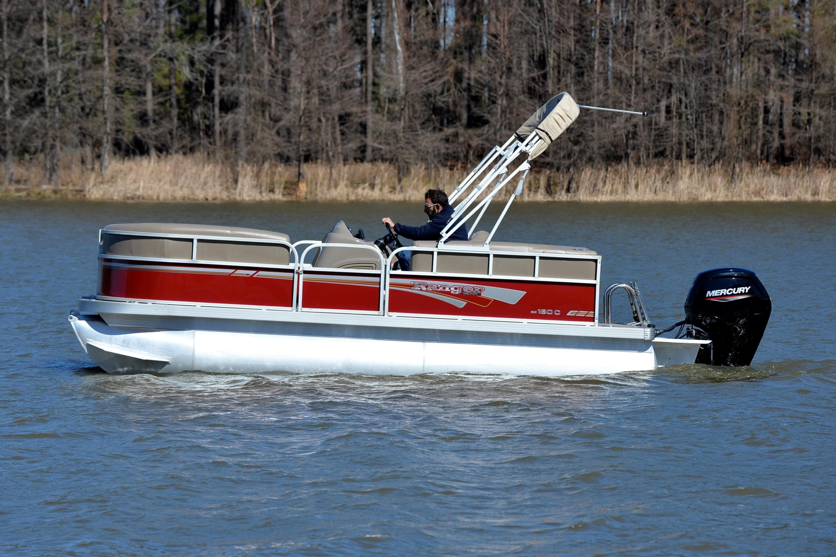 2021 Ranger 180 Reata pontoon boat cruising on a lake with trees in the background.