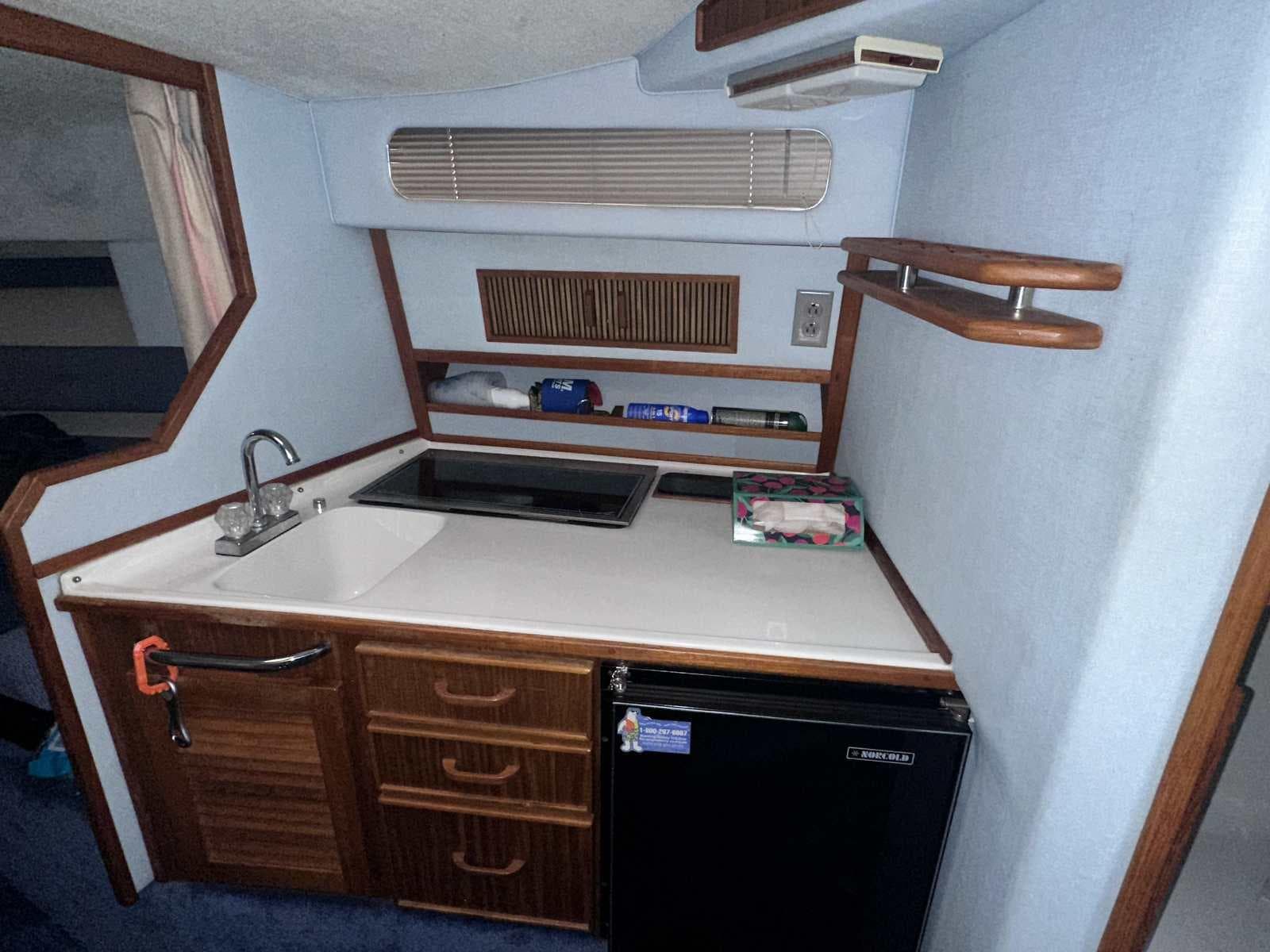 1987 Sea Ray 270 Sundancer cabin kitchen with sink, stove, and mini fridge.