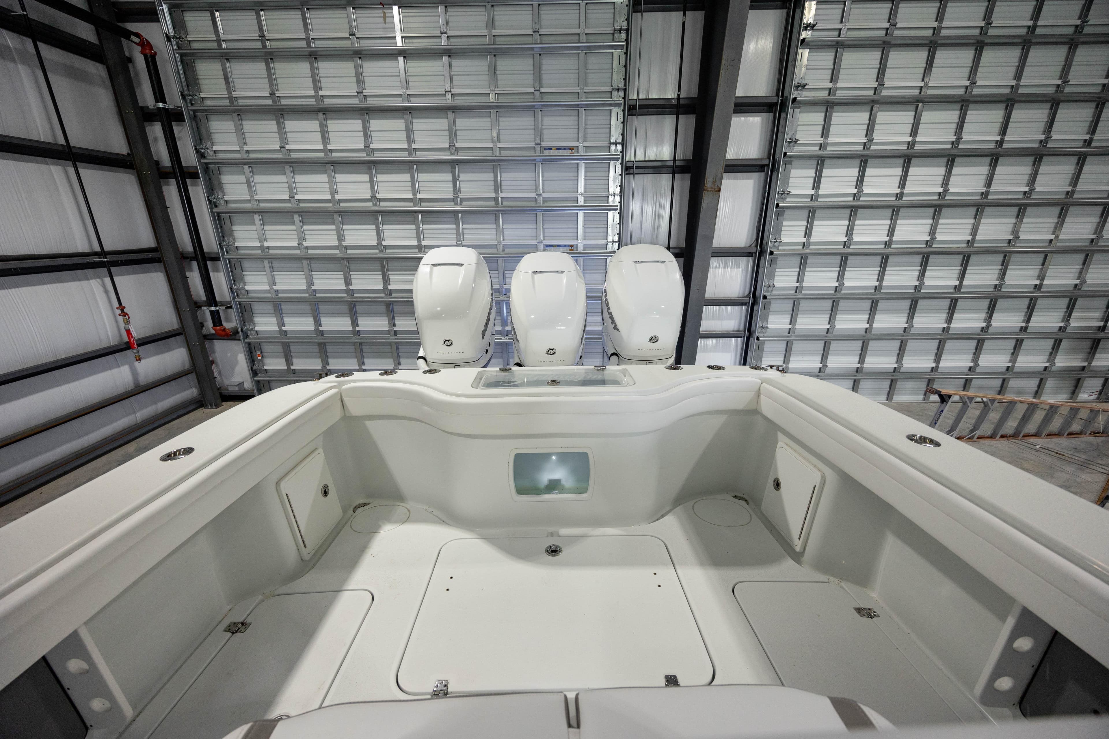 2022 Yellowfin 34 boat interior with triple outboard engines in a storage facility.