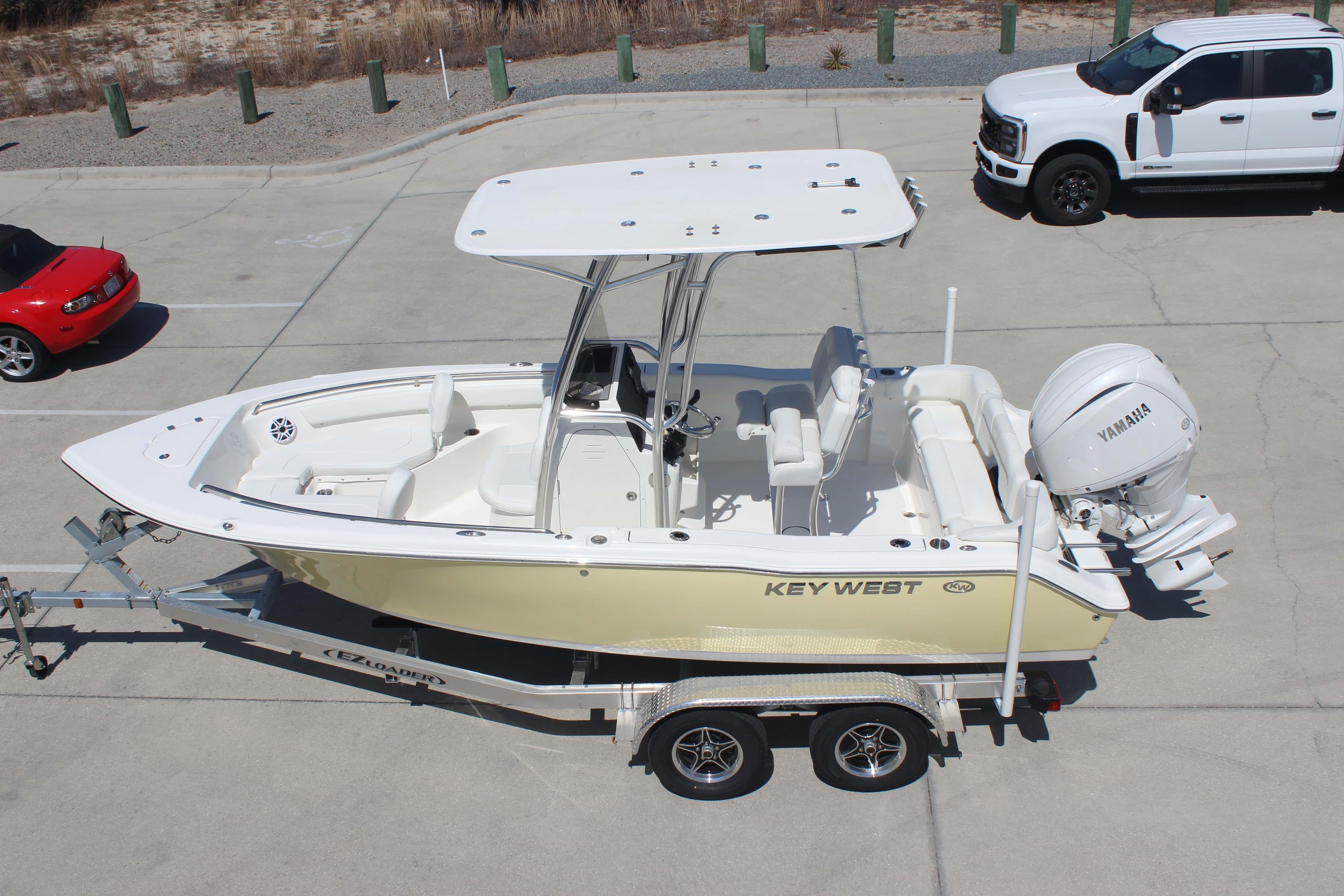 2026 Key West 203 FS boat on trailer, parked beside vehicles in a lot.