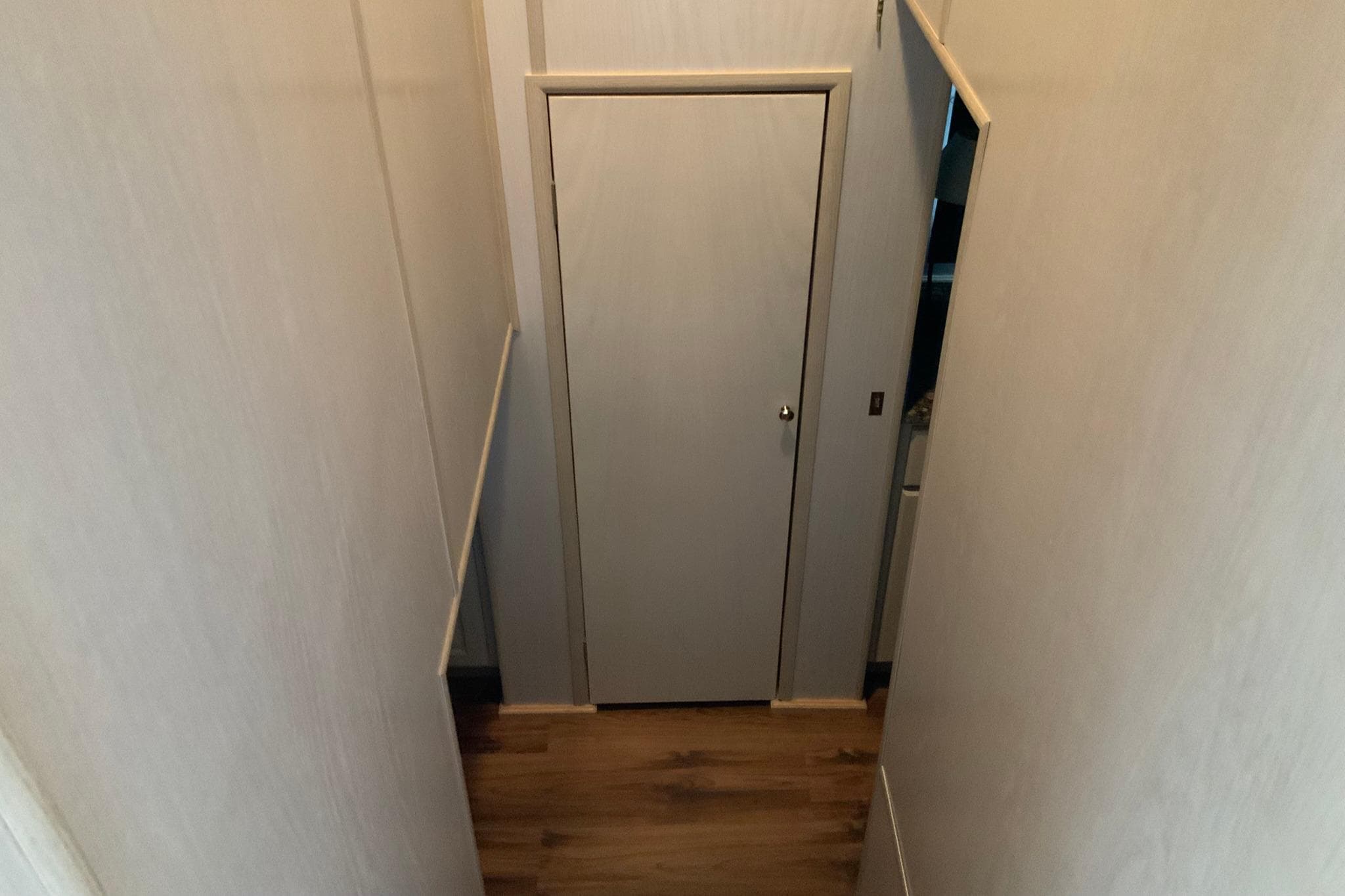 Narrow hallway with wooden floor and closed door in 1997 Lakeview 16 x 65 model.