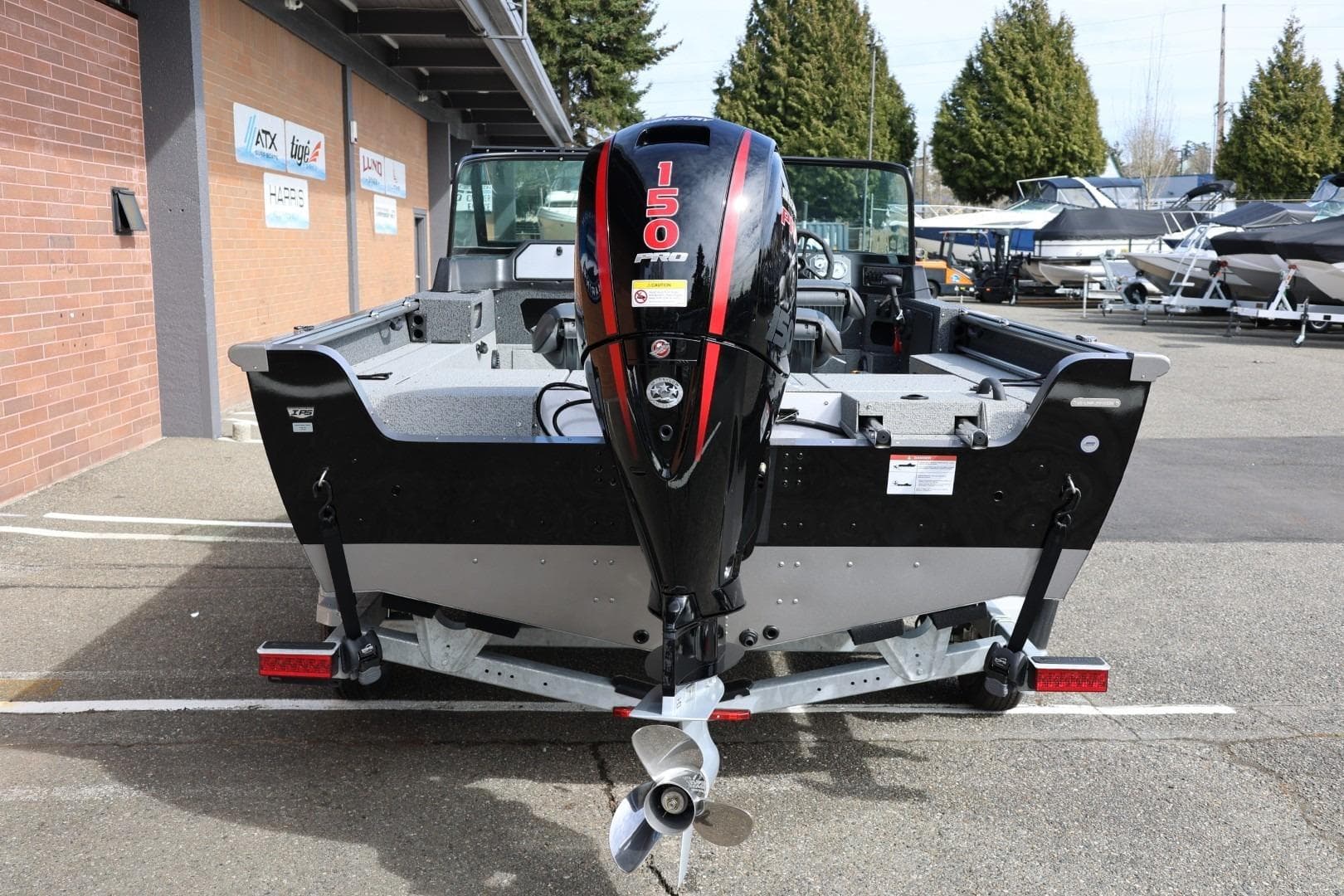 2026 Lund 1875 Impact XS Sport boat with 150 HP engine, parked outdoors.