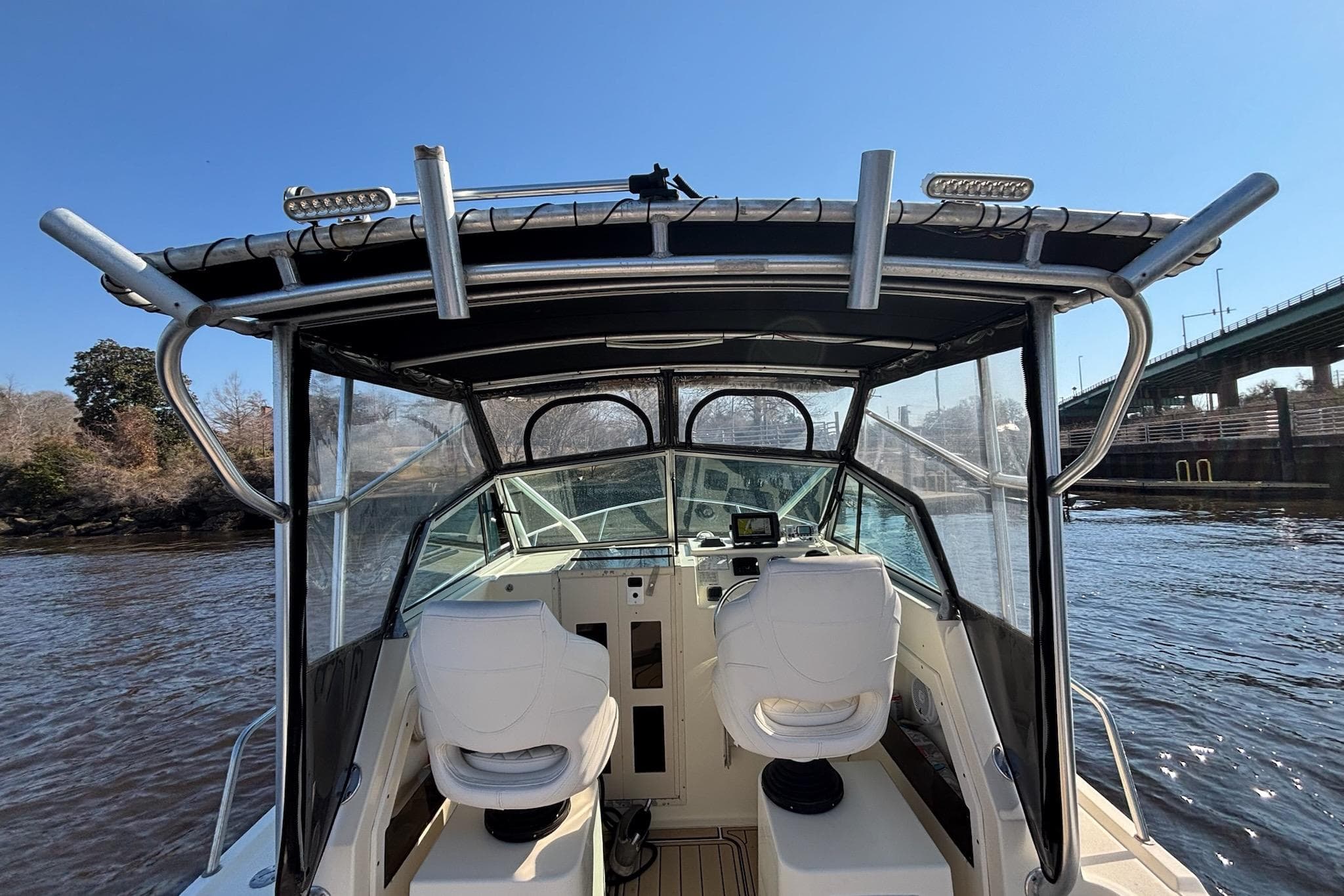 1996 Parker 2110 boat interior with dual seats, navigating a river near a bridge.