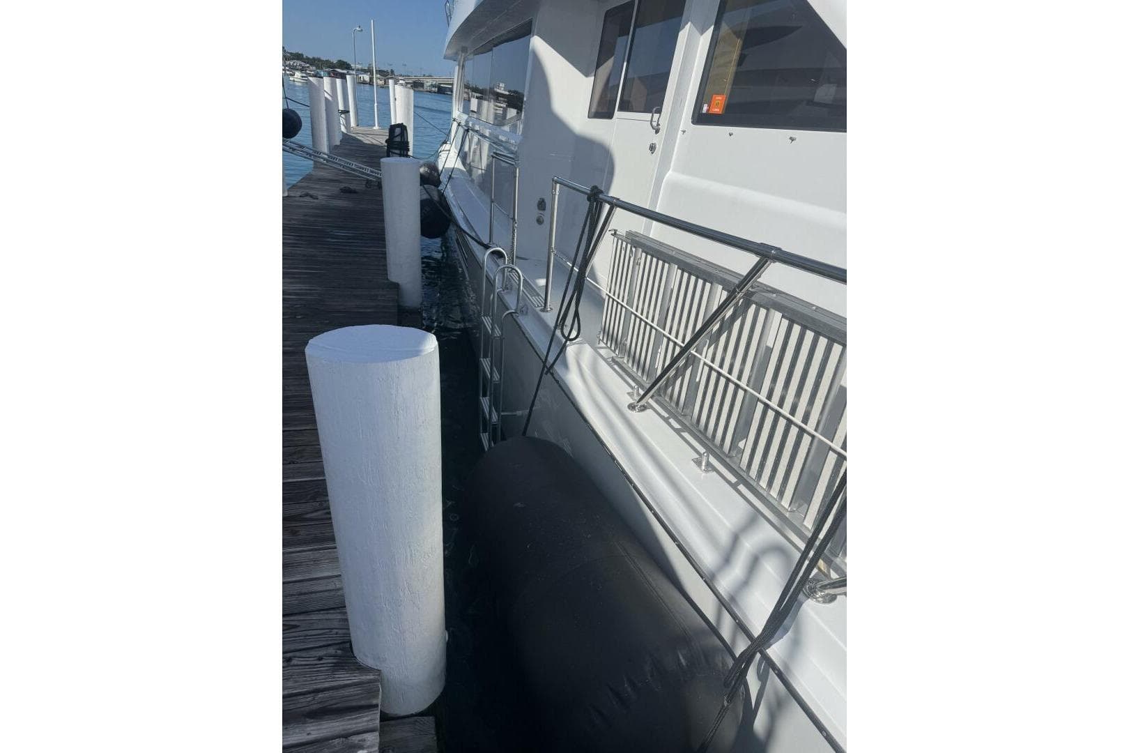 Hatteras 75 Sport Deck Motor Yacht 2000 docked at marina with fender protection.