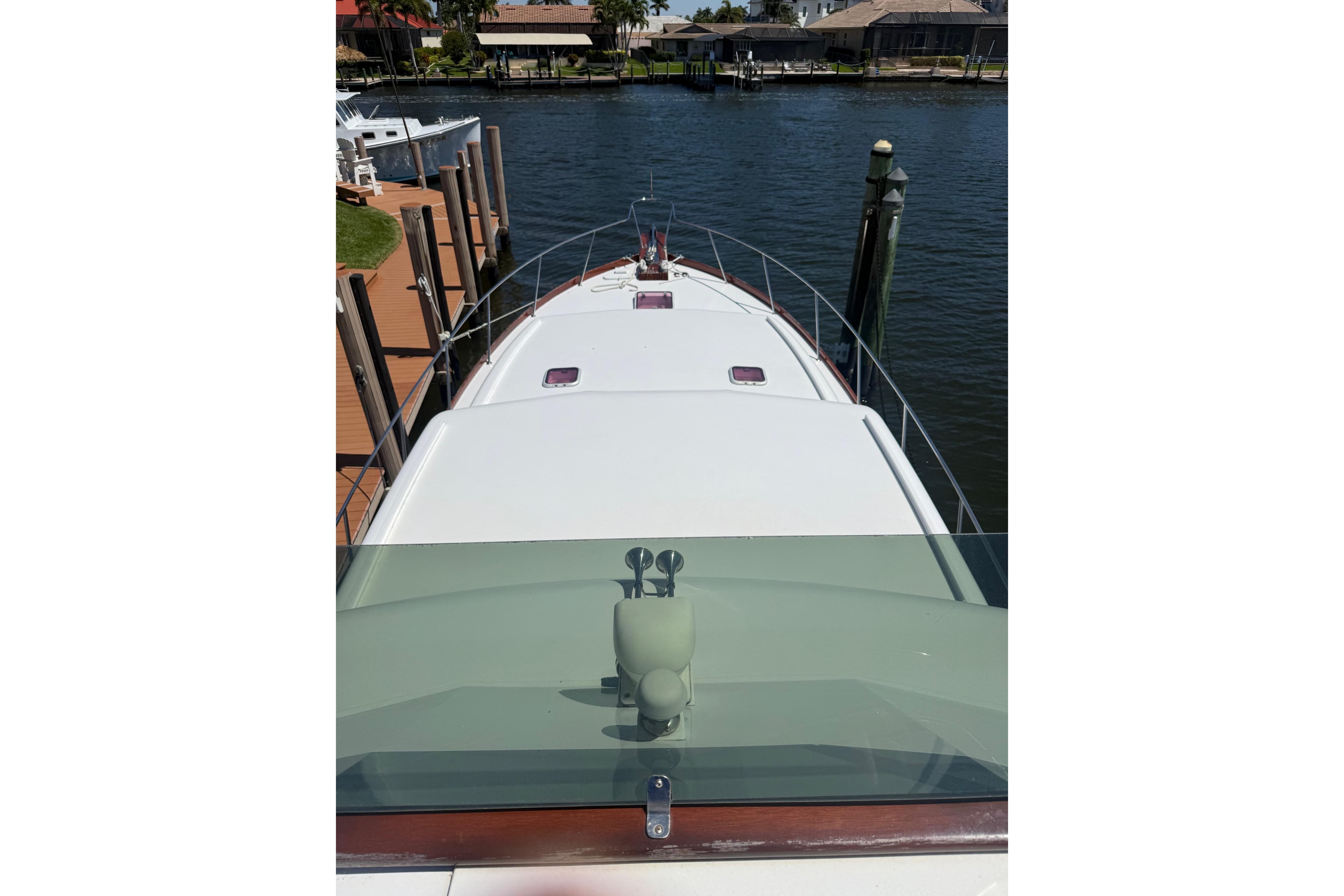 2006 Huckins Atlantic 44 yacht docked by waterfront homes.