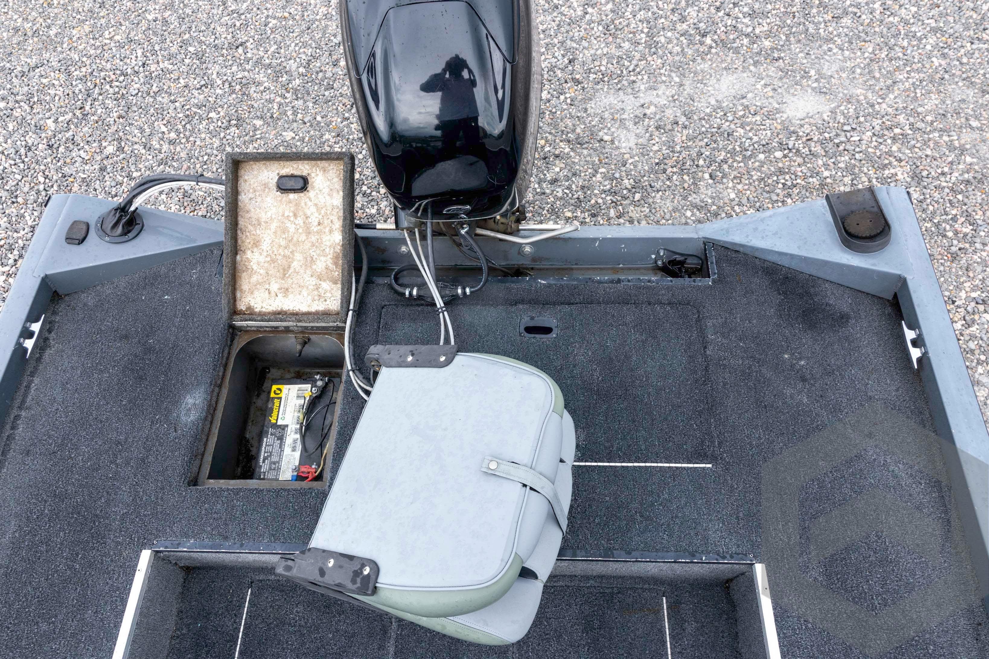2007 Triton TC-17 boat interior with open battery compartment and motor, on gravel surface.
