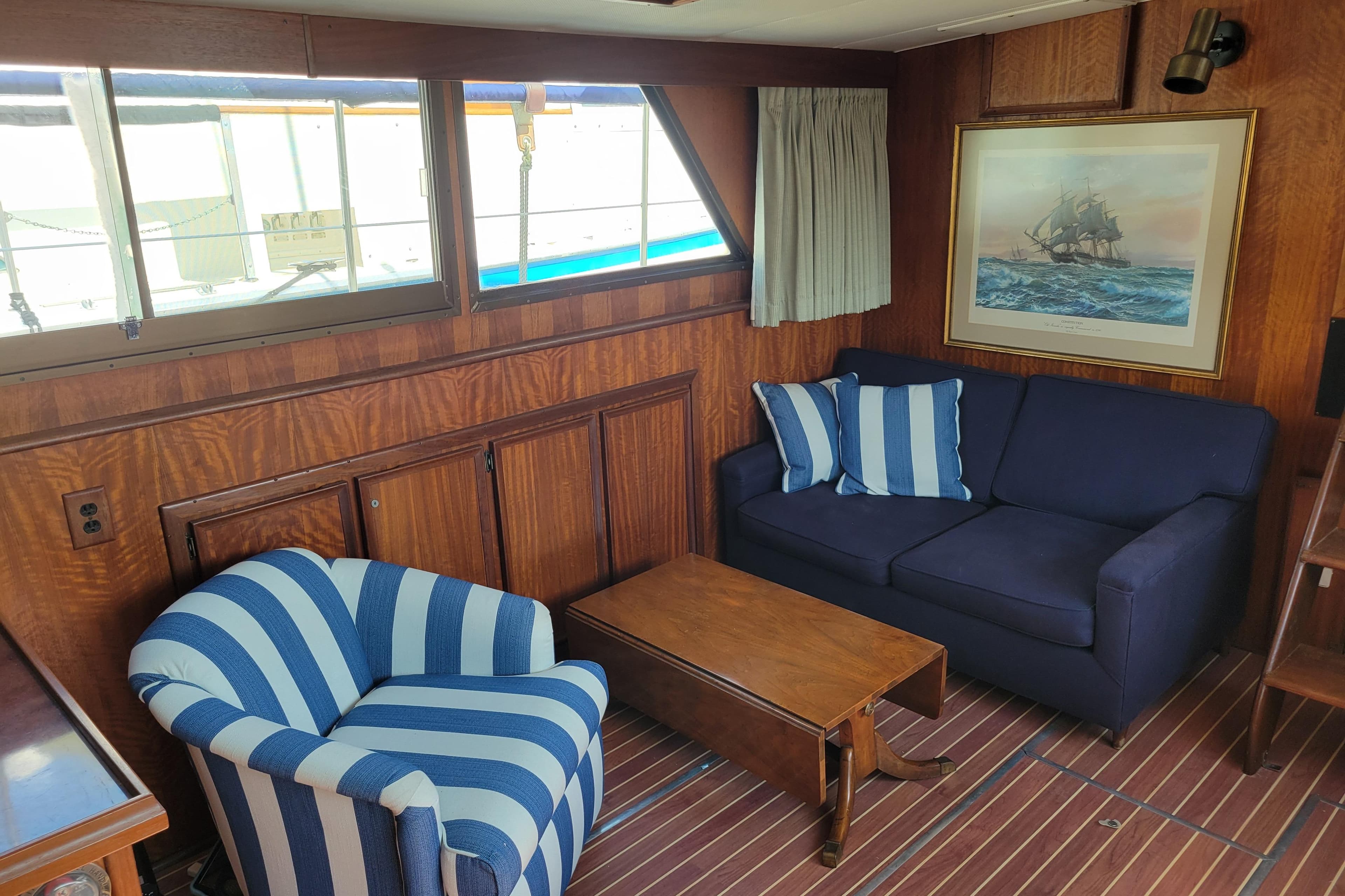 Interior of 1977 Hatteras 43 Double Cabin with striped chair, blue sofa, and nautical decor.