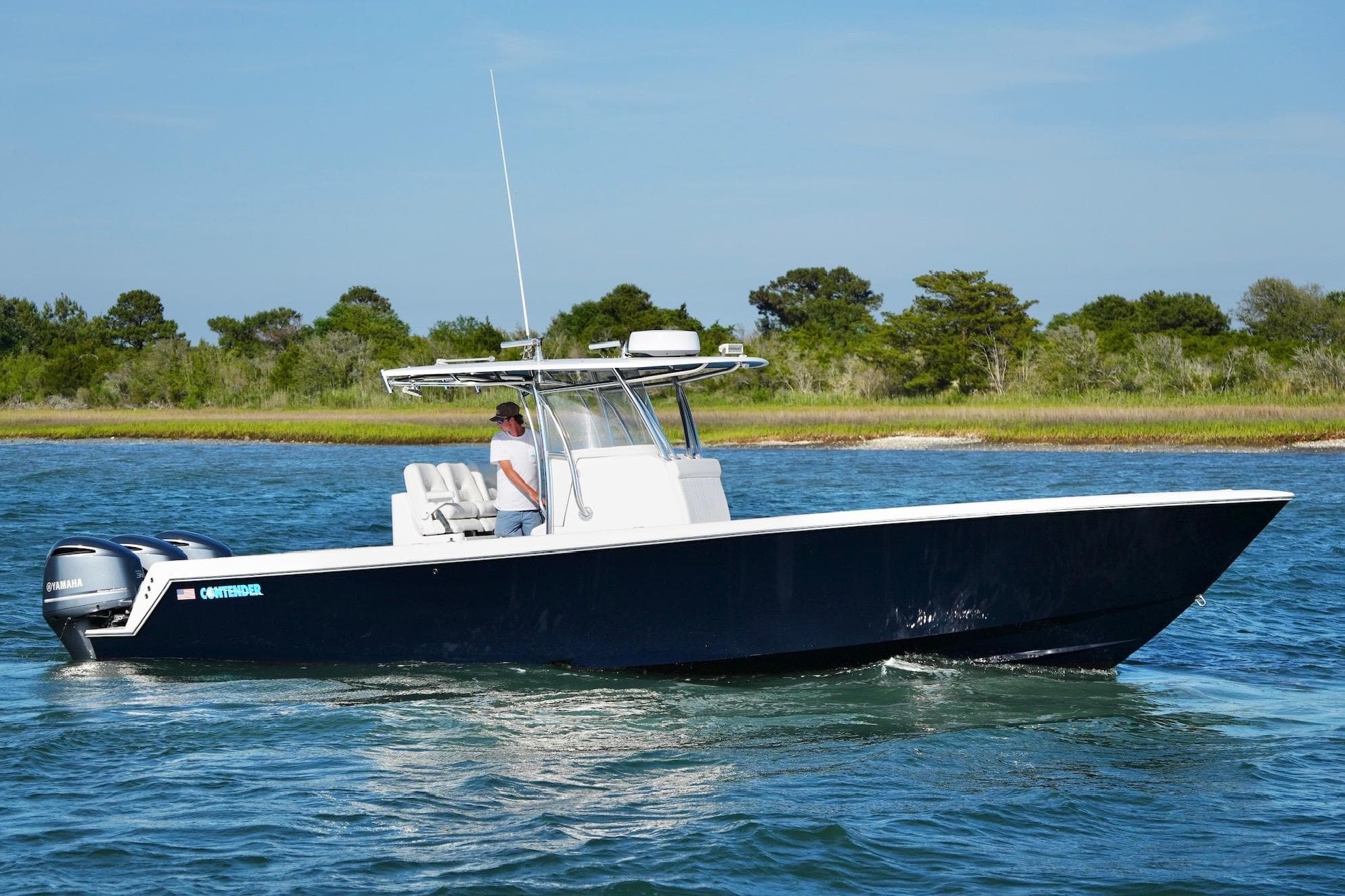 2019 Contender 35 ST boat cruising on a scenic waterway with lush greenery.