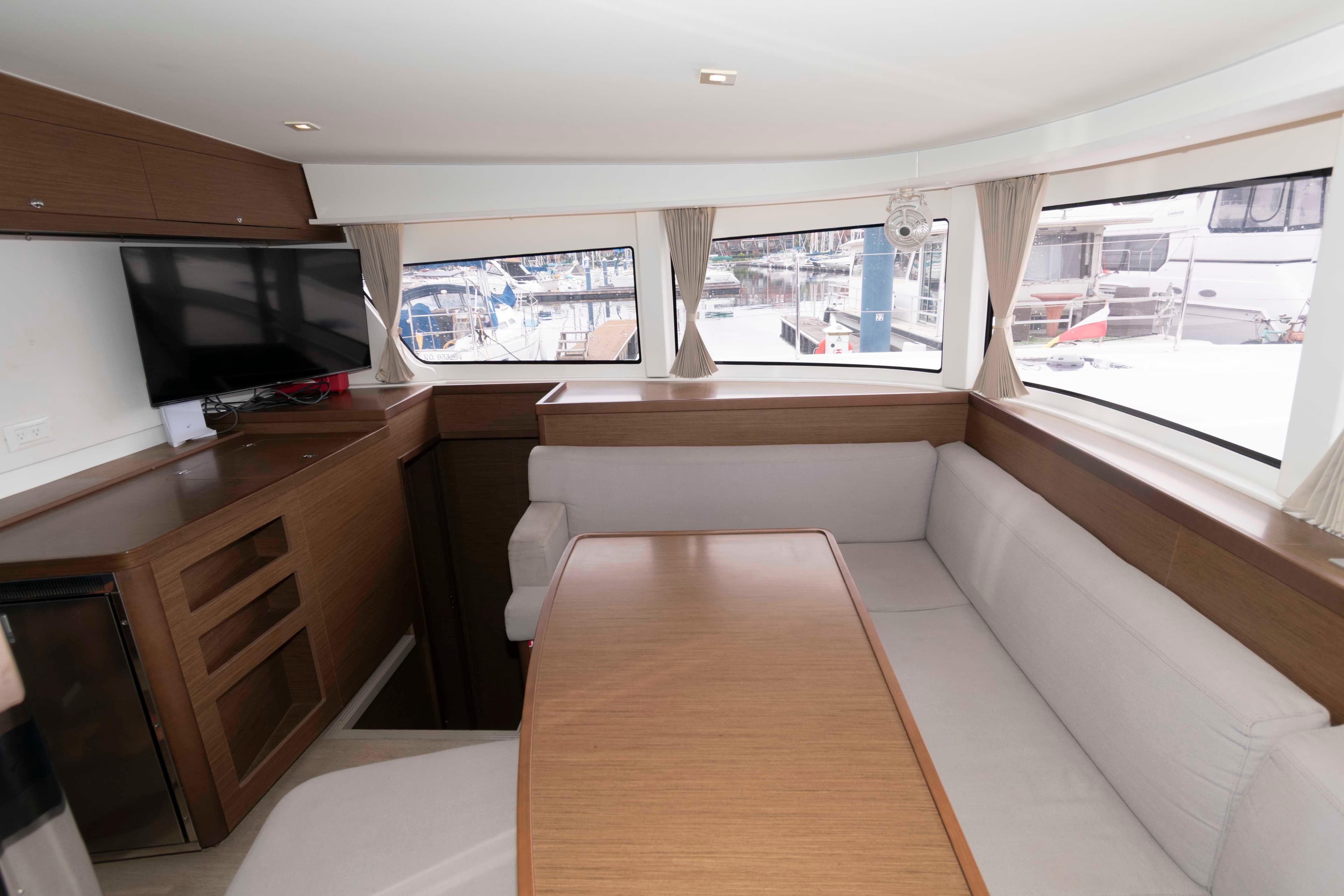 Interior of 2019 Lagoon 42 yacht with dining area and panoramic windows.