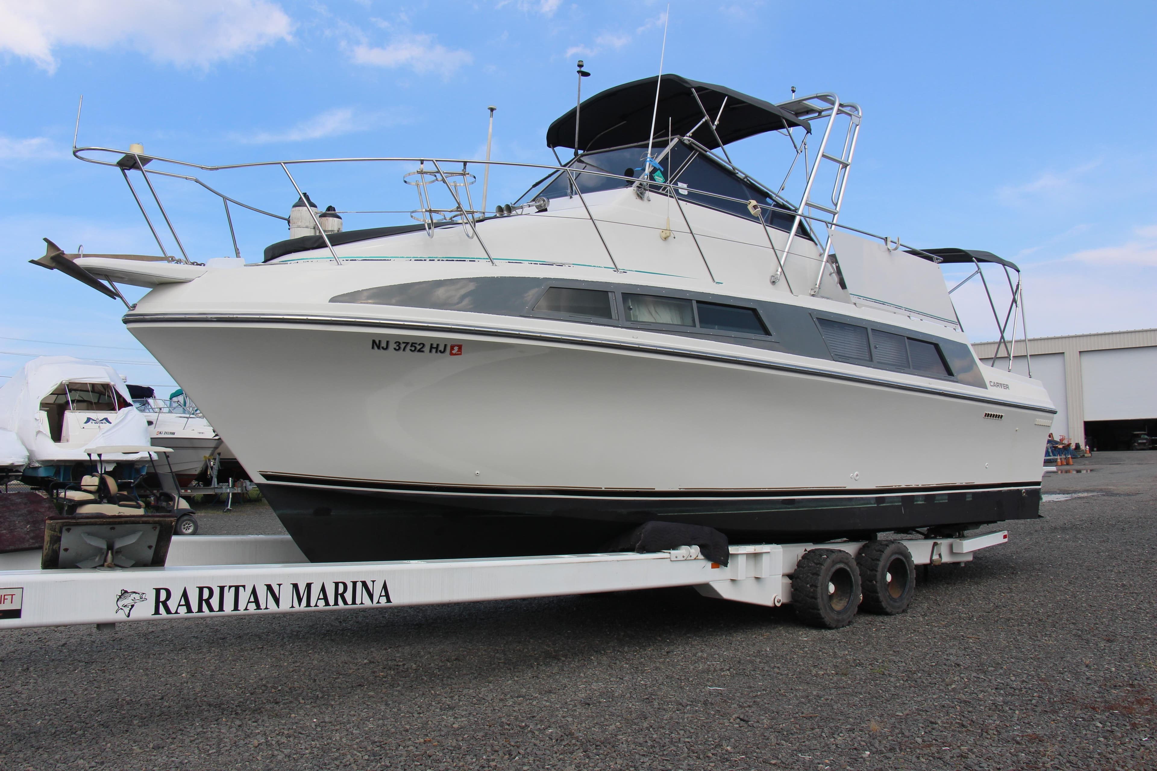 1995 Carver 330 Mariner yacht on trailer at Raritan Marina, clear sky background.