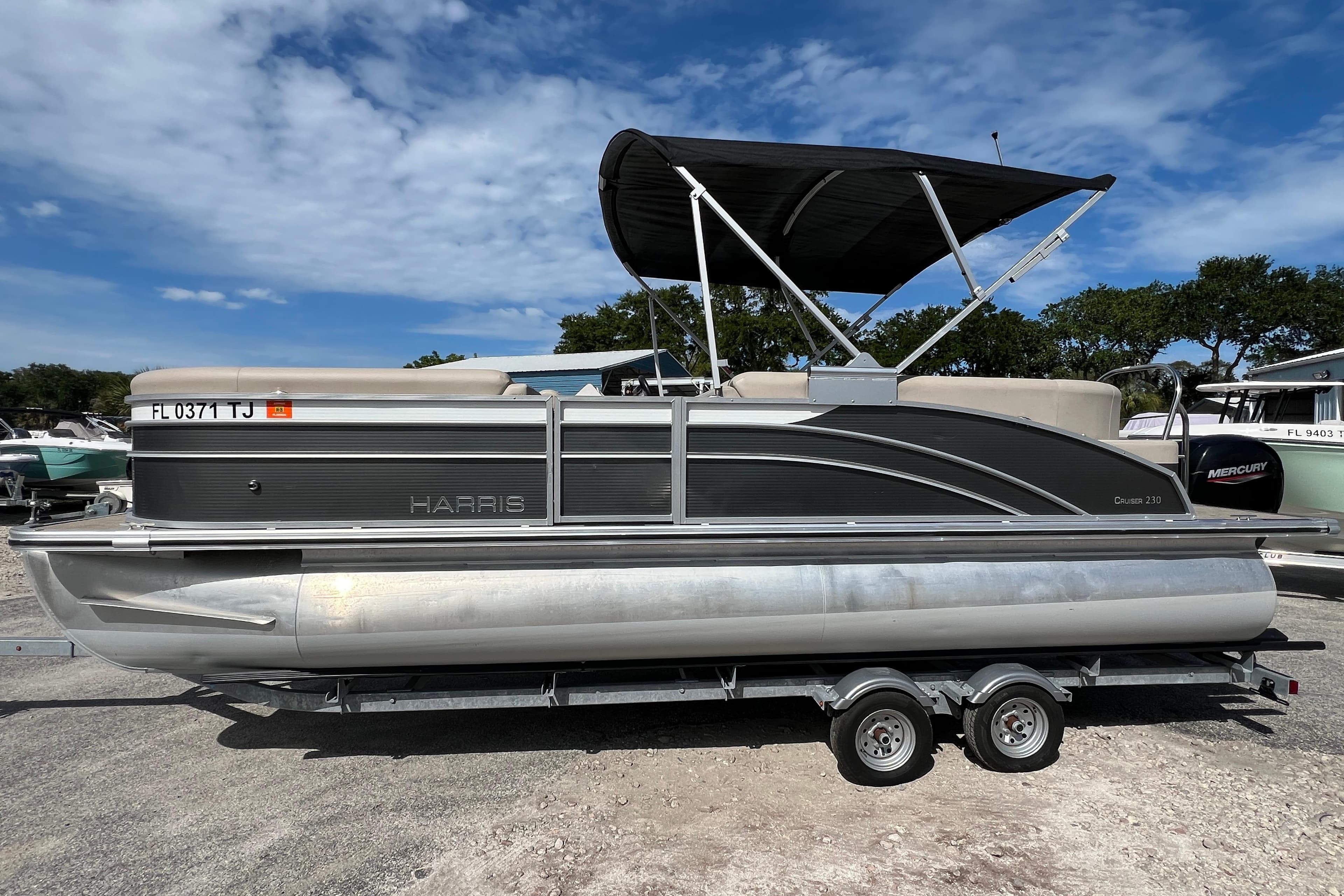 2023 Harris Cruiser 230 pontoon boat on trailer under blue sky.