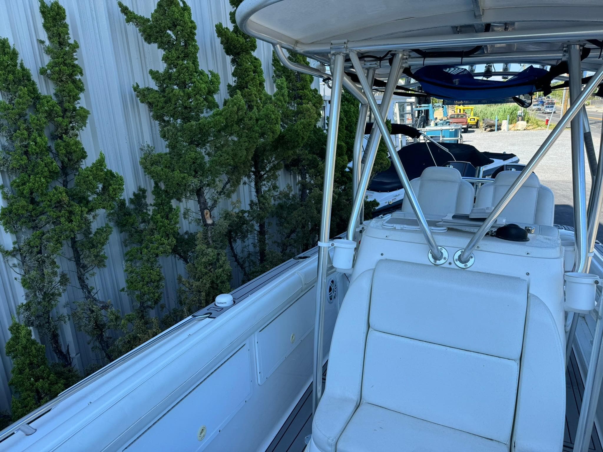 1998 Wellcraft Scarab Sport 302 boat with white seating and metal framework, docked near greenery.