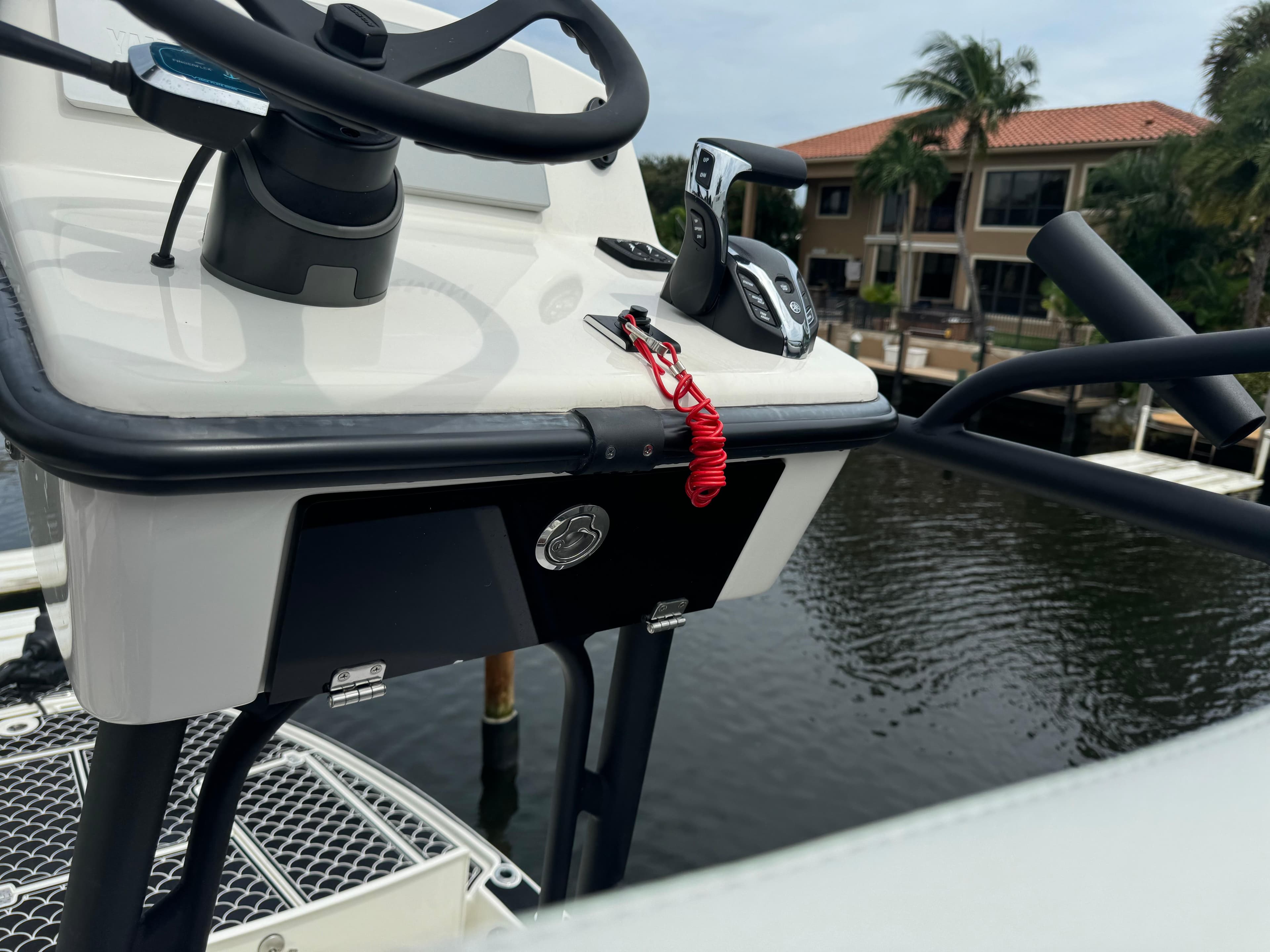 2024 Pathfinder 2500 Hybrid boat console with steering wheel and controls, docked by waterfront homes.