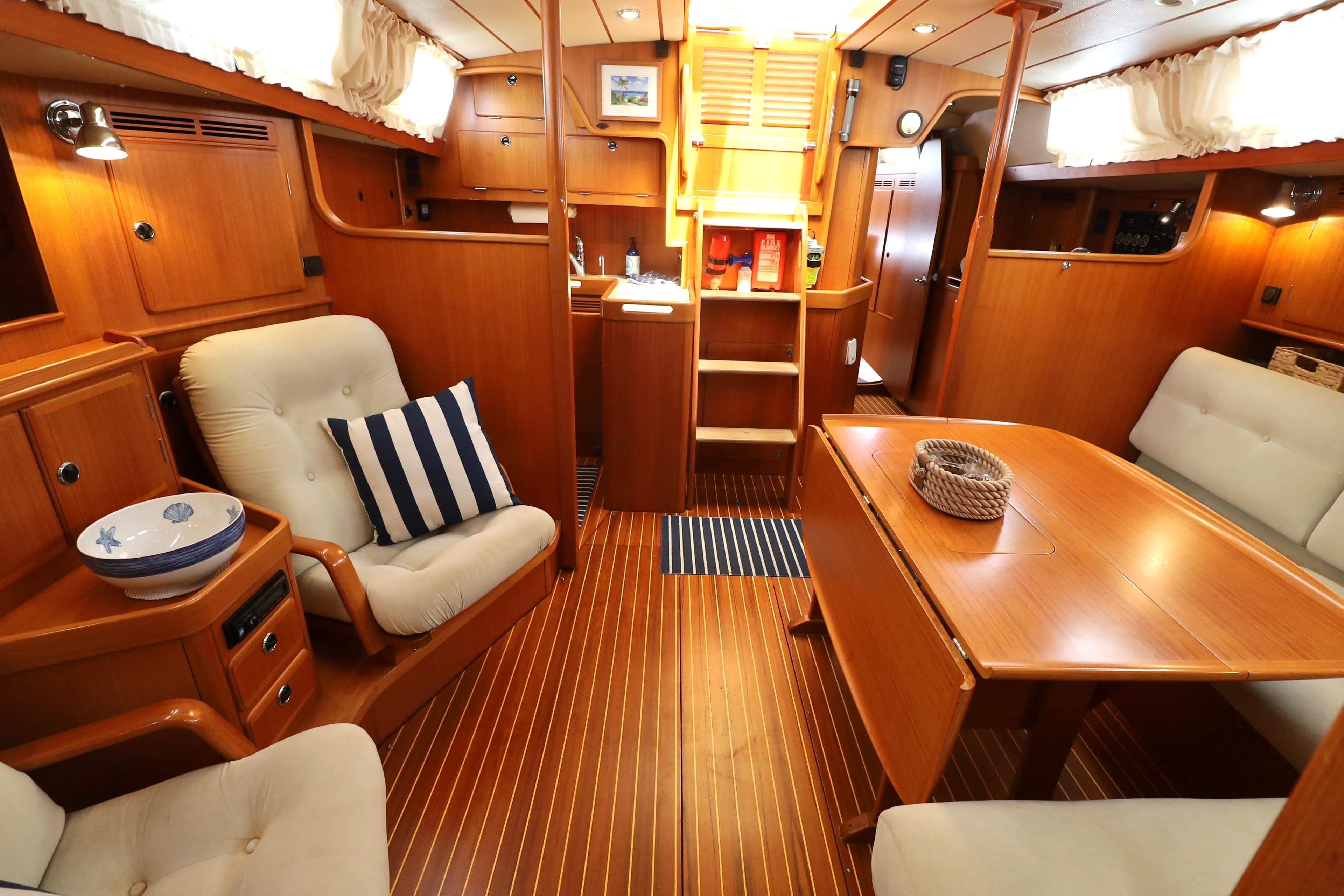 Luxurious interior of 2000 Hallberg-Rassy 46 yacht with wooden furnishings and cozy seating.