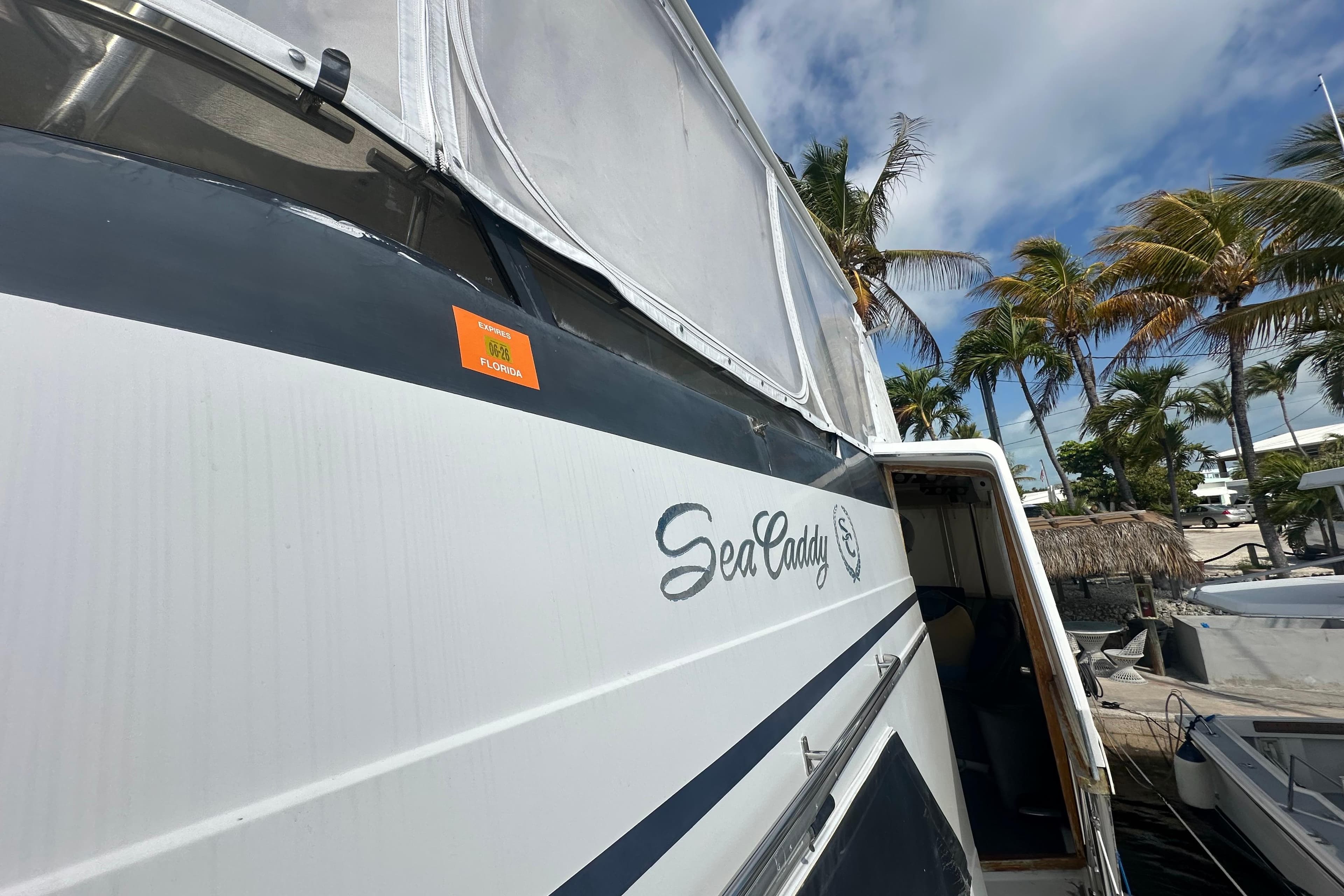 1991 Carver Californian 48 yacht docked, featuring "Sea Caddy" name, palm trees in background.