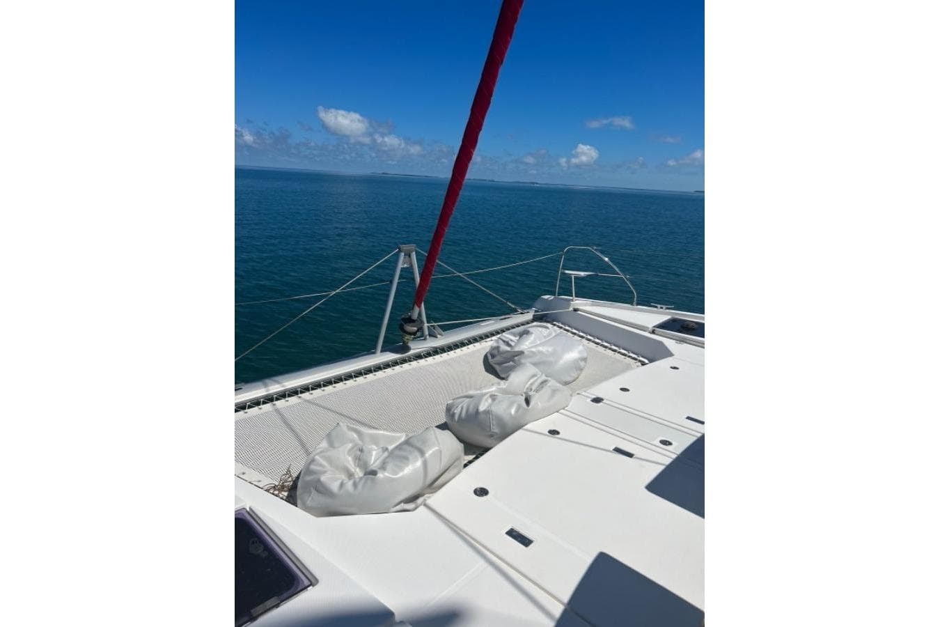 Catamaran deck view on a 2018 Leopard 45, sailing in clear blue waters.