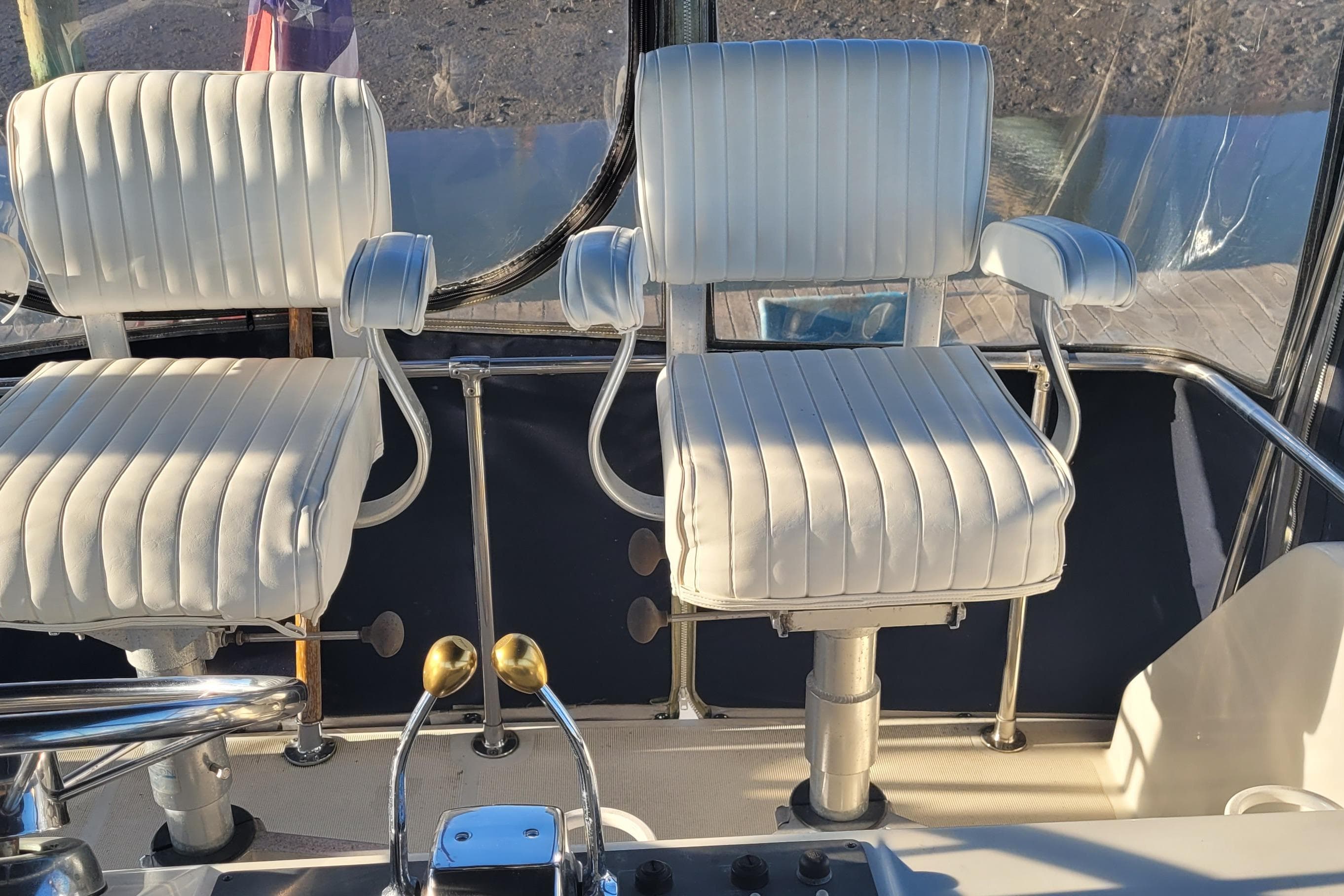 Captain's chairs on 1988 Tiara Yachts 3600 Convertible, featuring white upholstery and control levers.