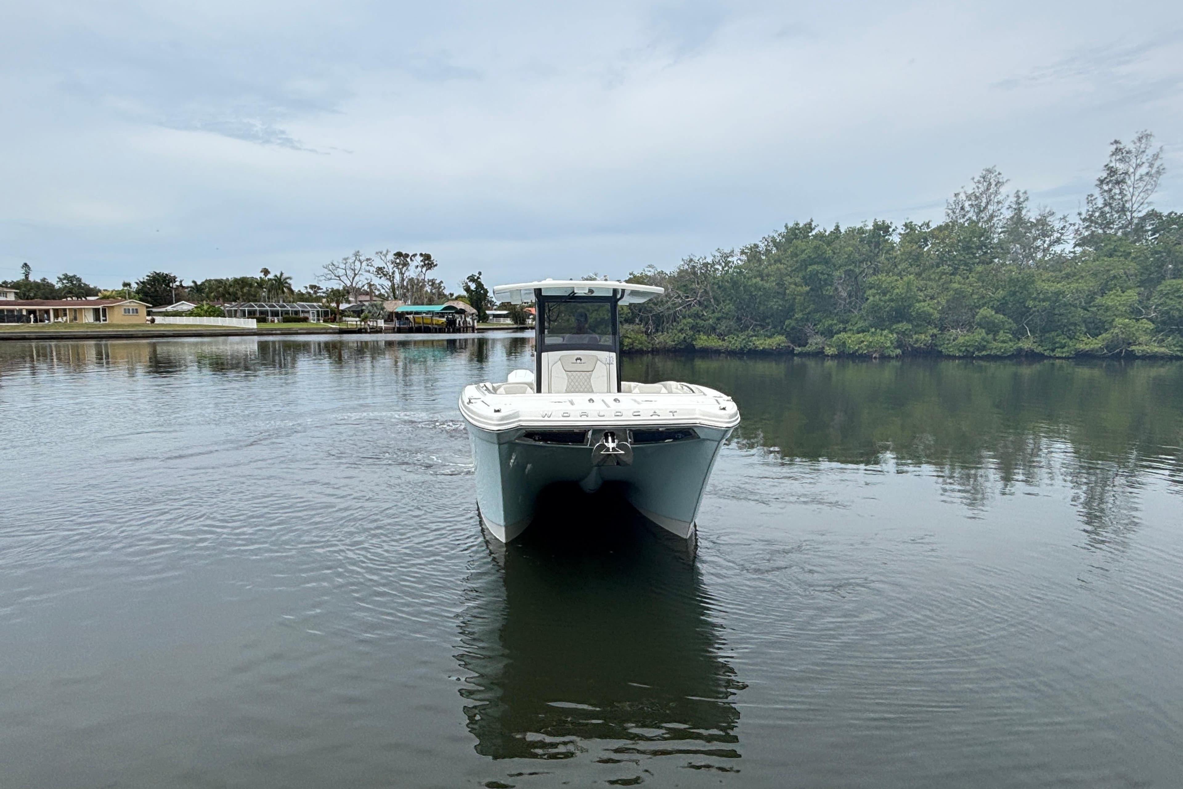 2026 World Cat 280 CC-X boat on calm water, surrounded by lush greenery.
