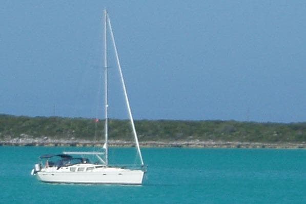 Sailboat Jeanneau Sun Odyssey 43 DS, 2002 model, on turquoise waters with distant shoreline.