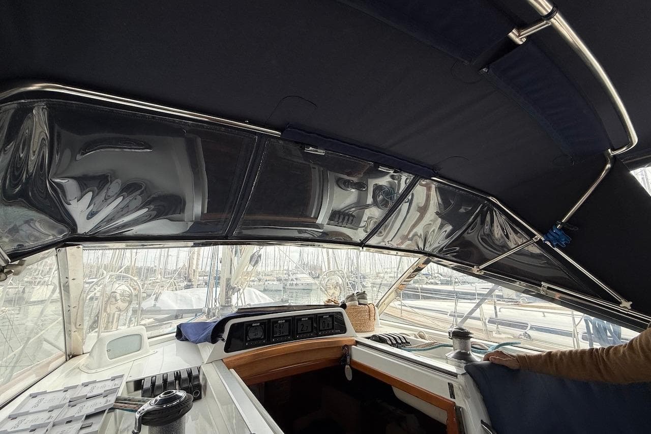 Cockpit view of a 2002 Moody 47 sailboat with protective canopy and marina background.