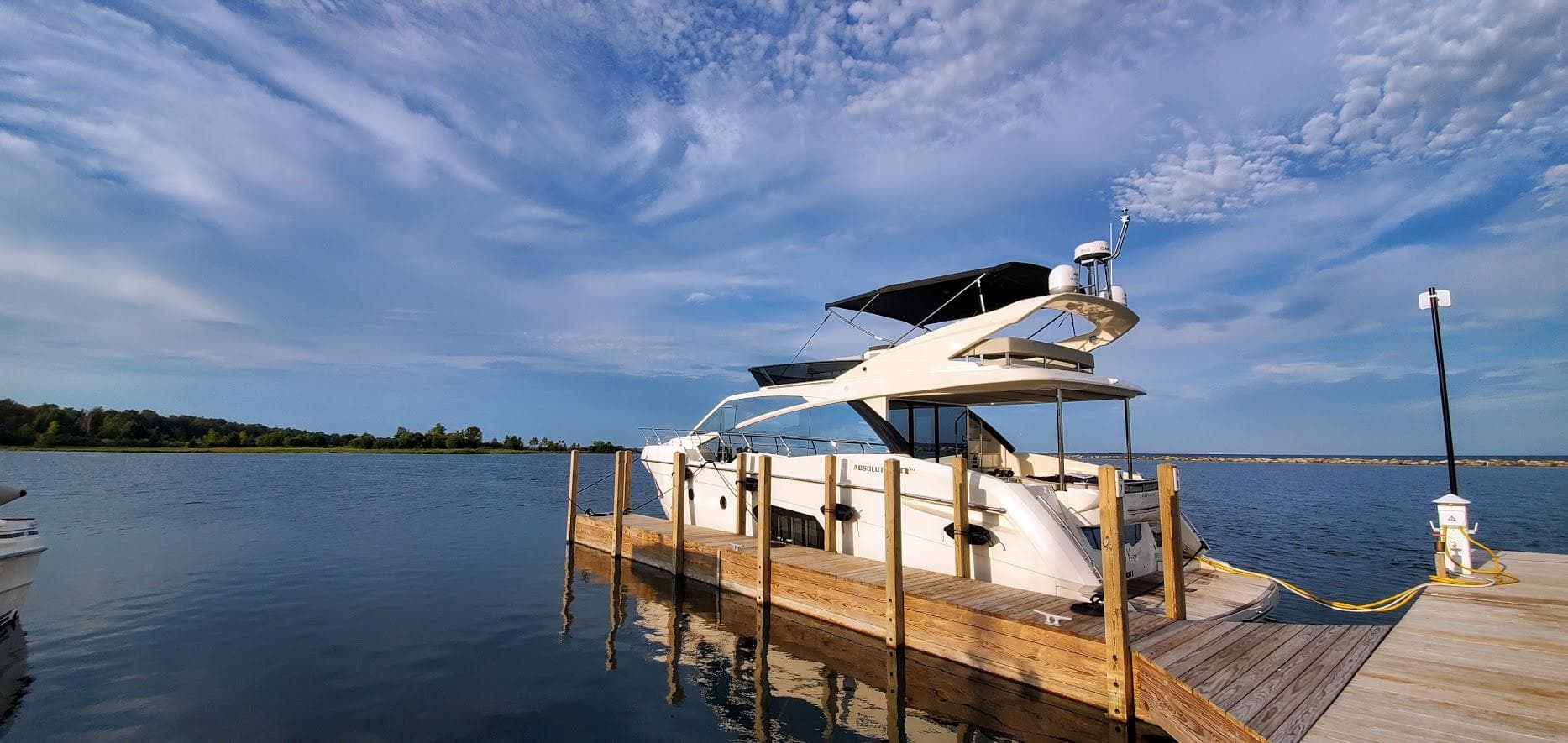 2019 Absolute 50 Fly yacht docked on calm water under a blue sky.