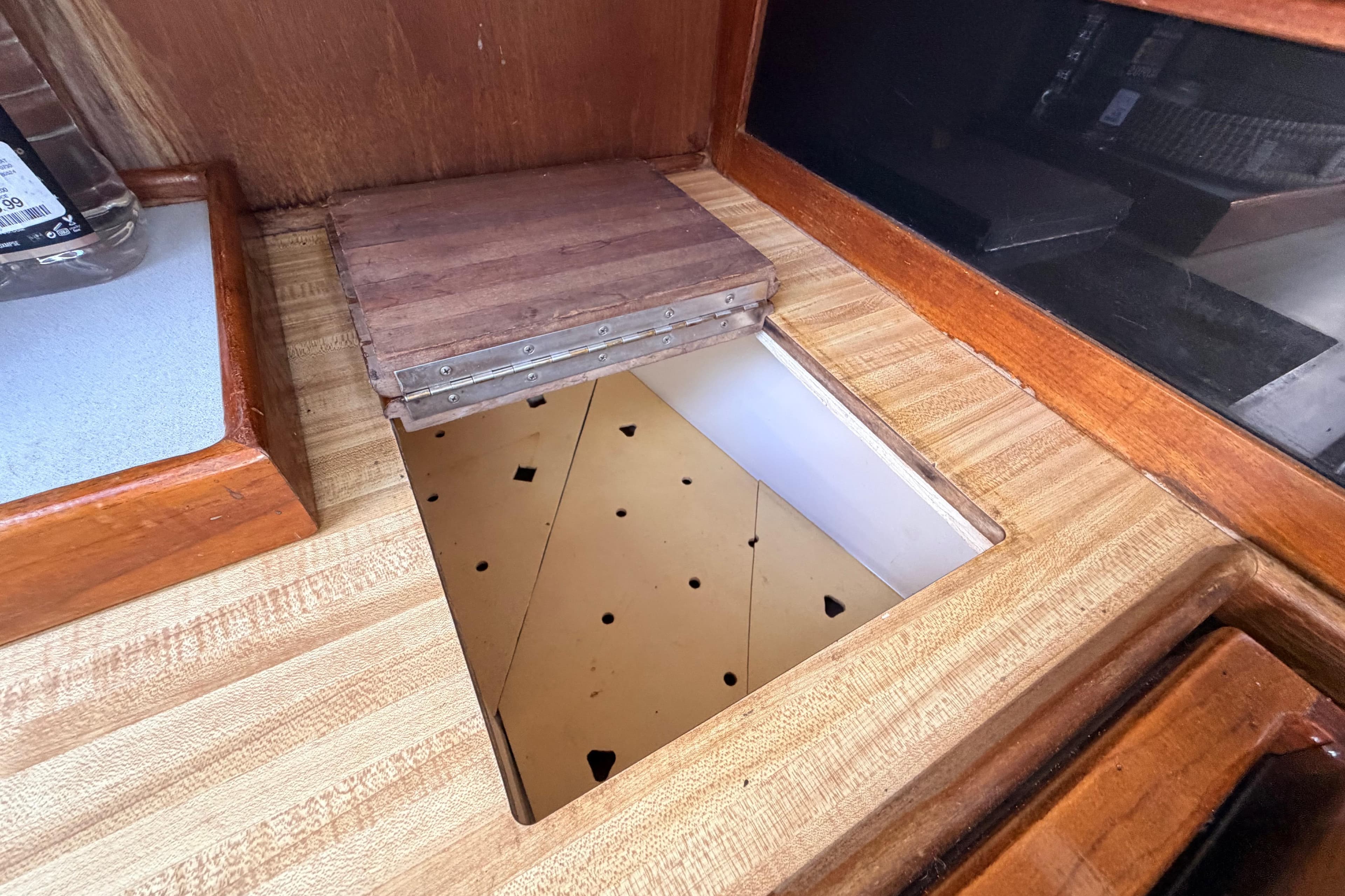 Interior view of a 1981 Catalina 30 sailboat with wooden cabinetry and storage compartment.