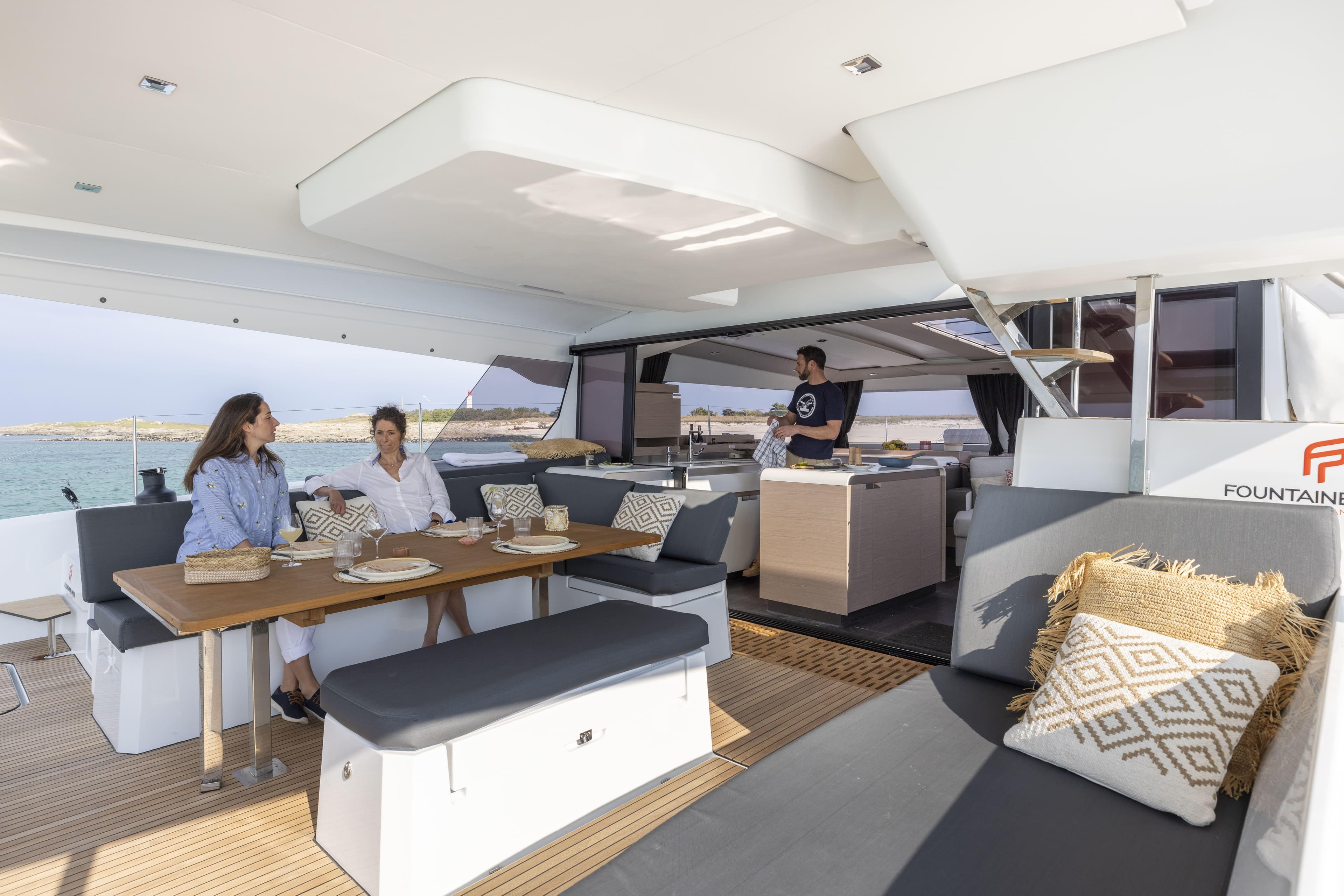 2025 Fountaine Pajot Aura 51 yacht interior with people dining and relaxing.