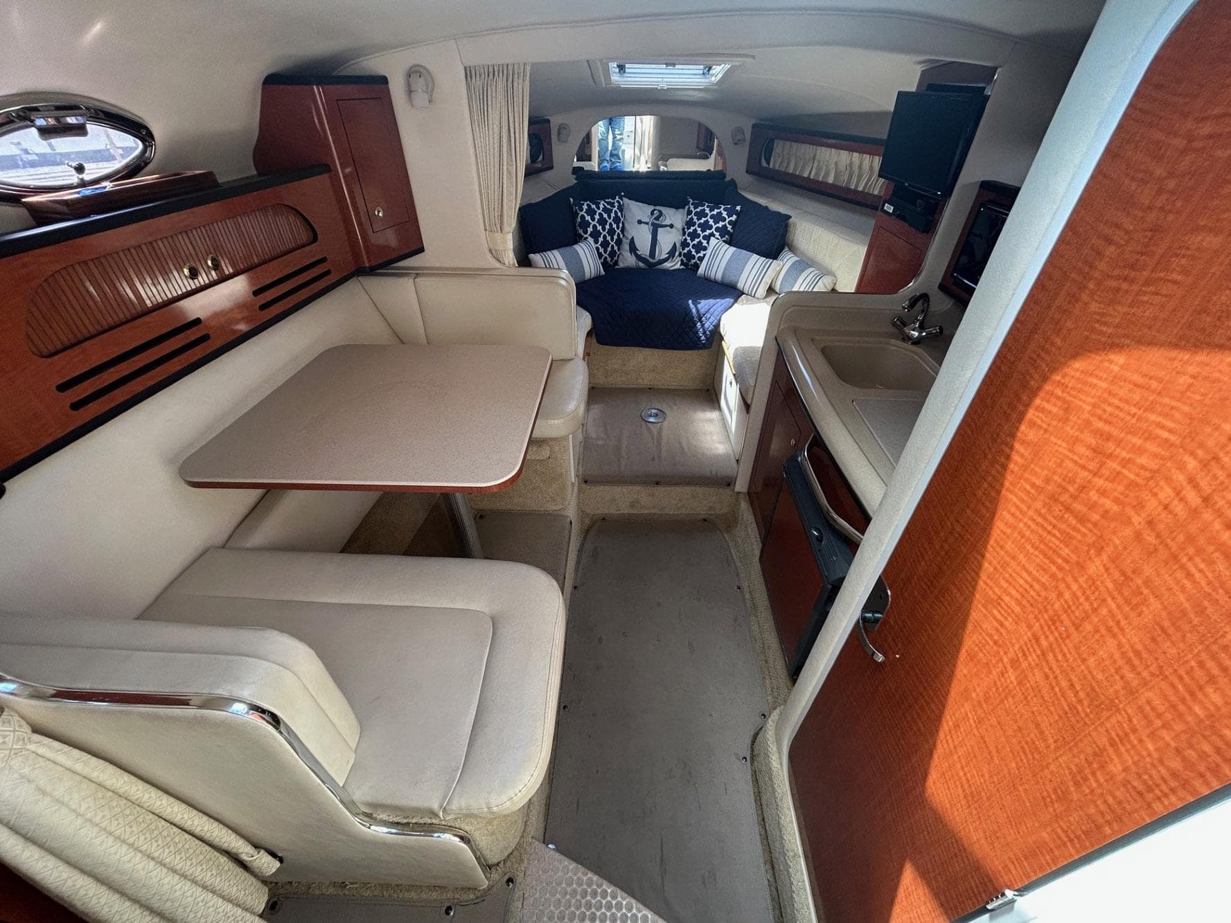 2004 Sea Ray 280 Sundancer cabin interior with dining area, kitchenette, and cozy seating.