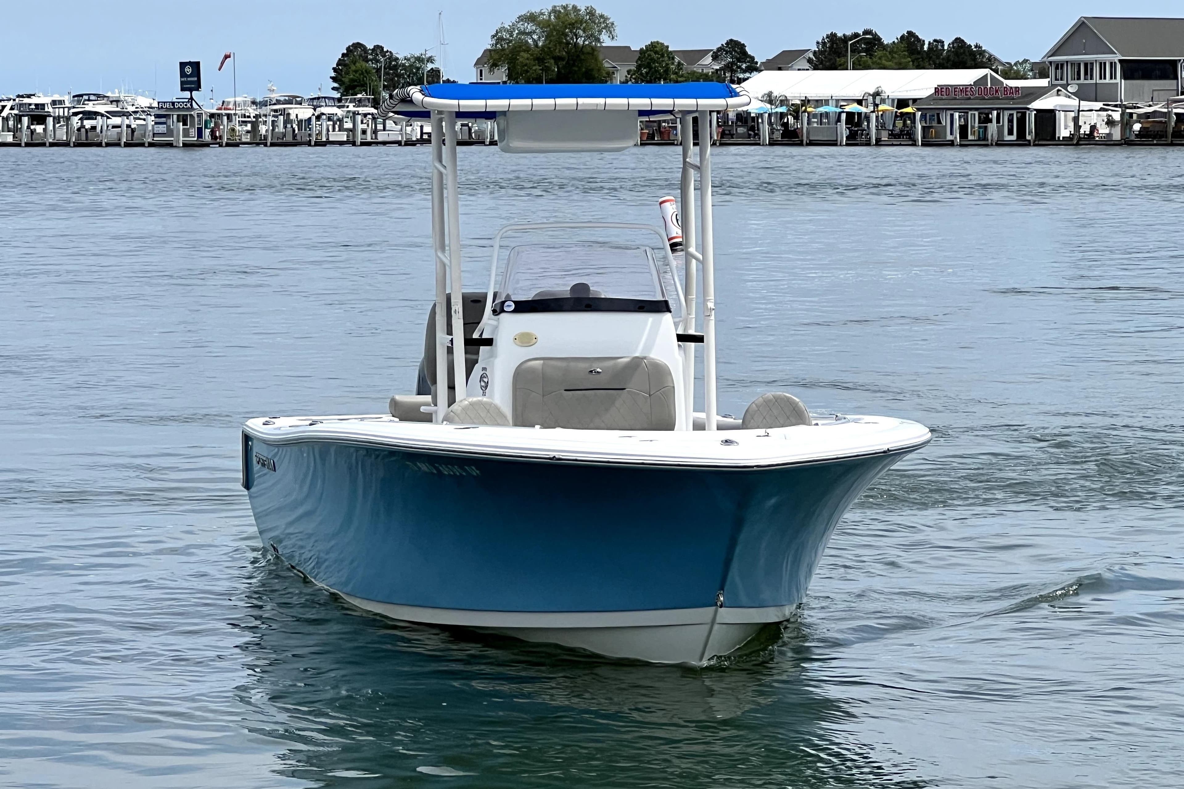2022 Sportsman Open 212 Center Console boat on calm water near a marina.