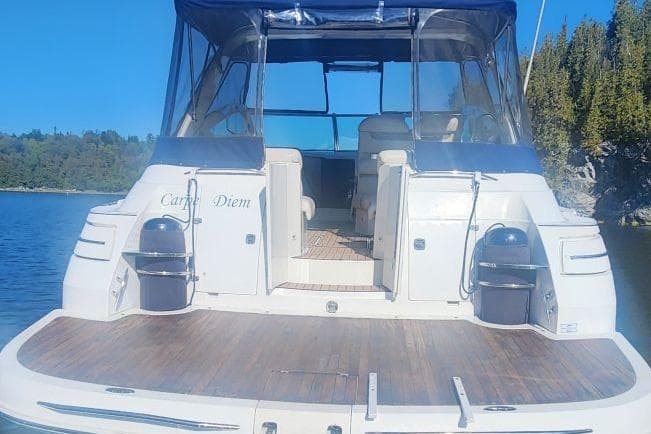 1999 Doral 360 SE Sunbridge boat on water, rear view with canopy and seating.