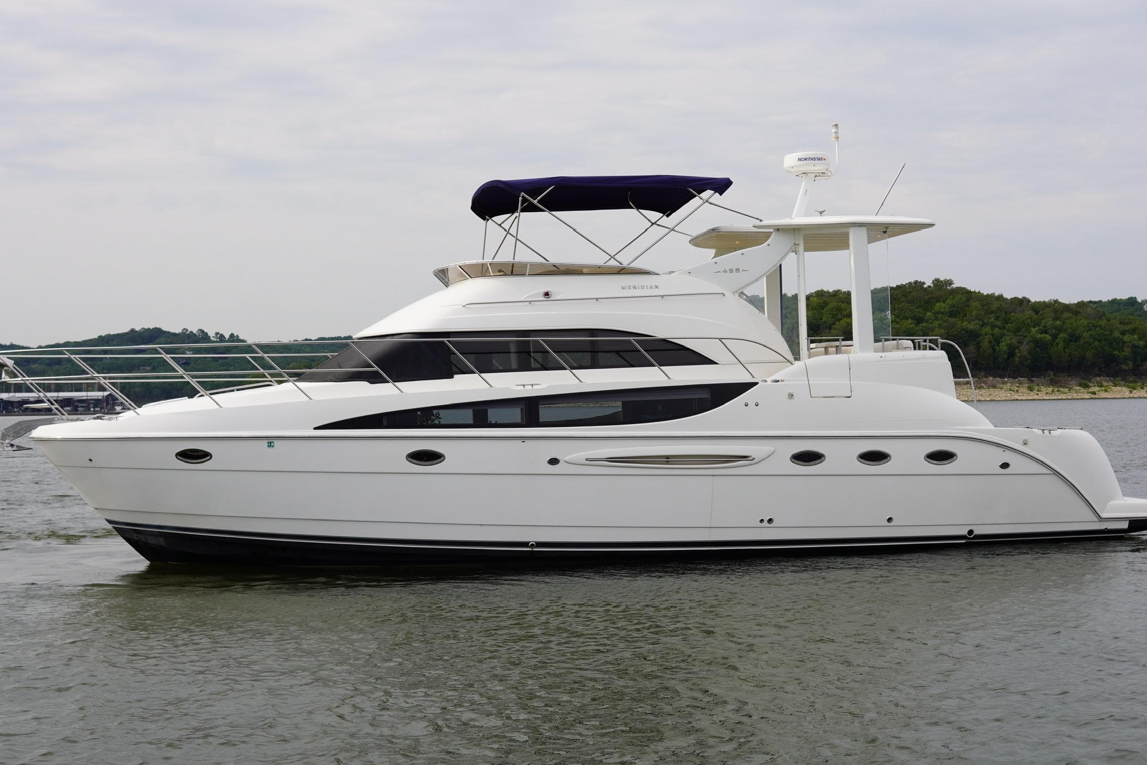 2008 Meridian 459 Motoryacht on calm water, side view with lush green shoreline.