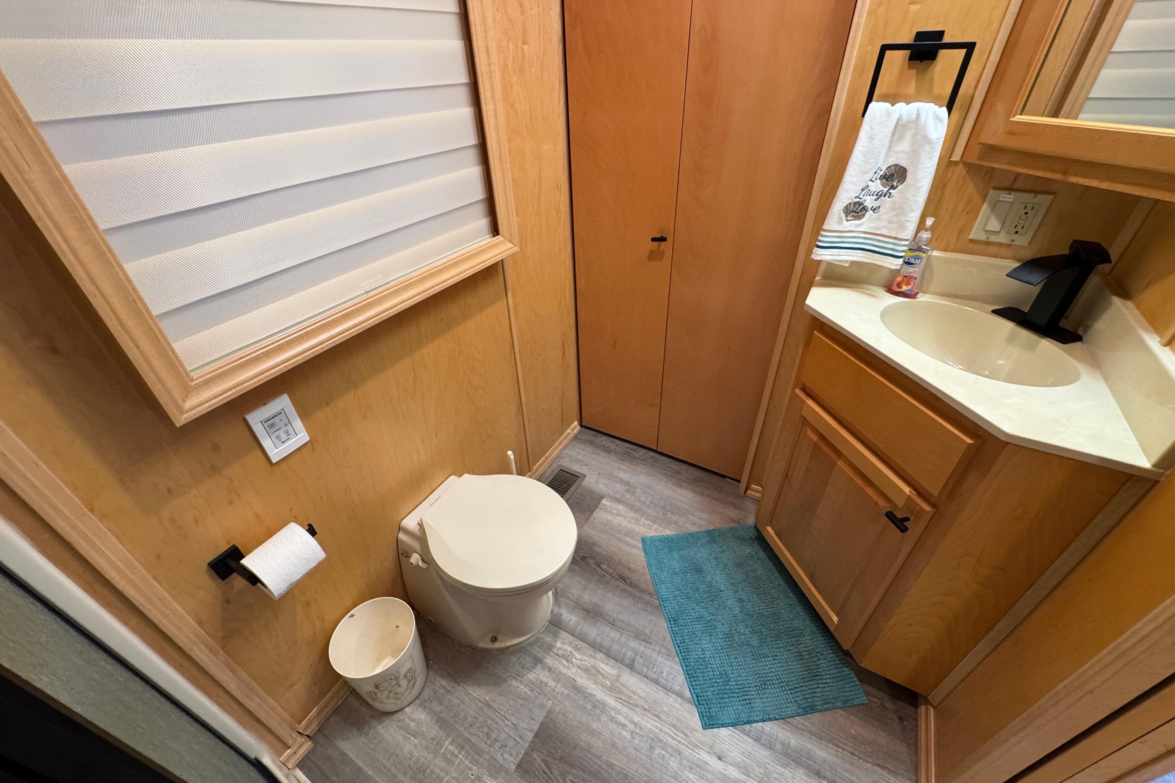 Compact bathroom in 2004 Starlite 65x16, featuring toilet, sink, and wooden cabinetry.