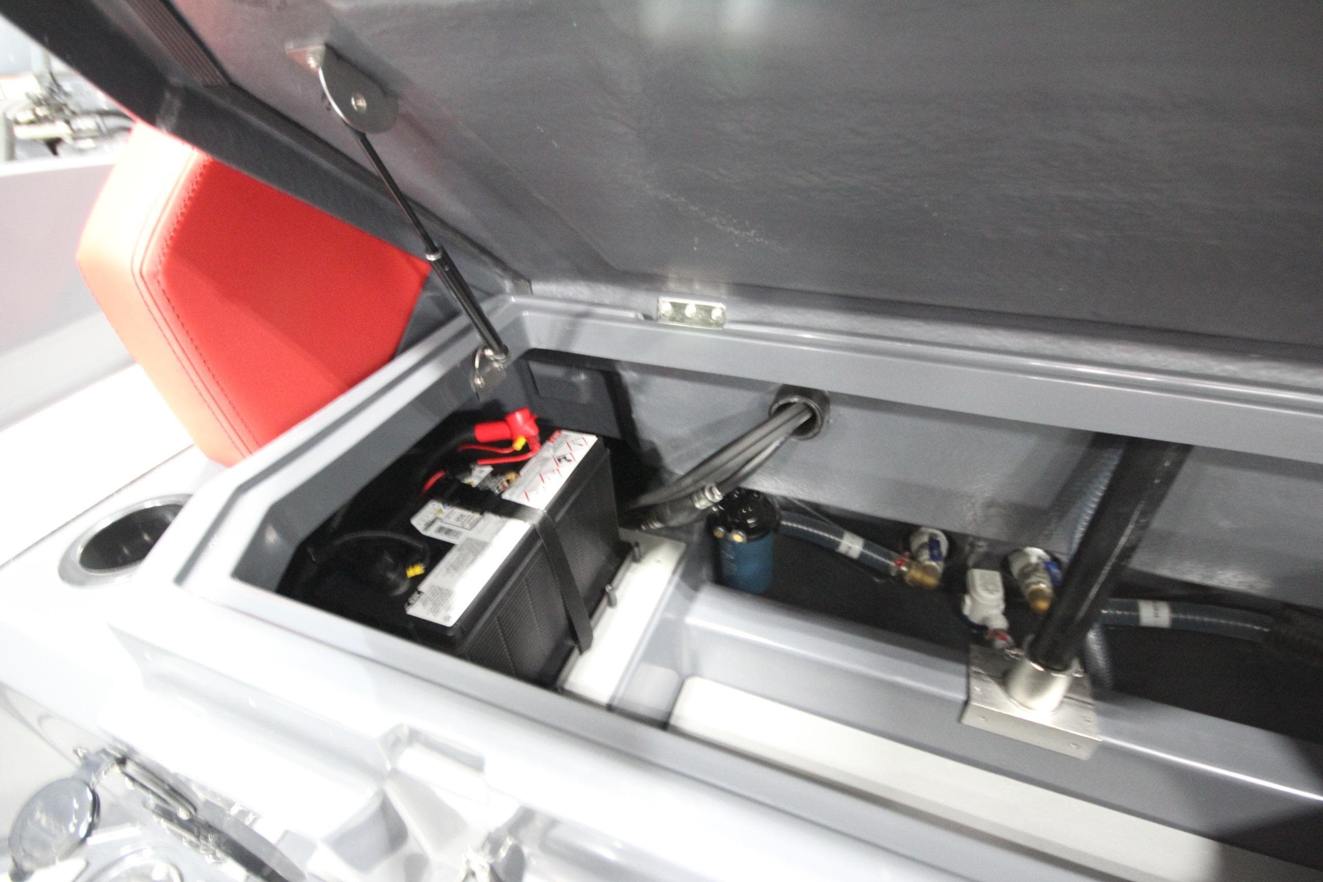 Open storage compartment in 2026 Iron 827 T-Top boat, showing battery and wiring.
