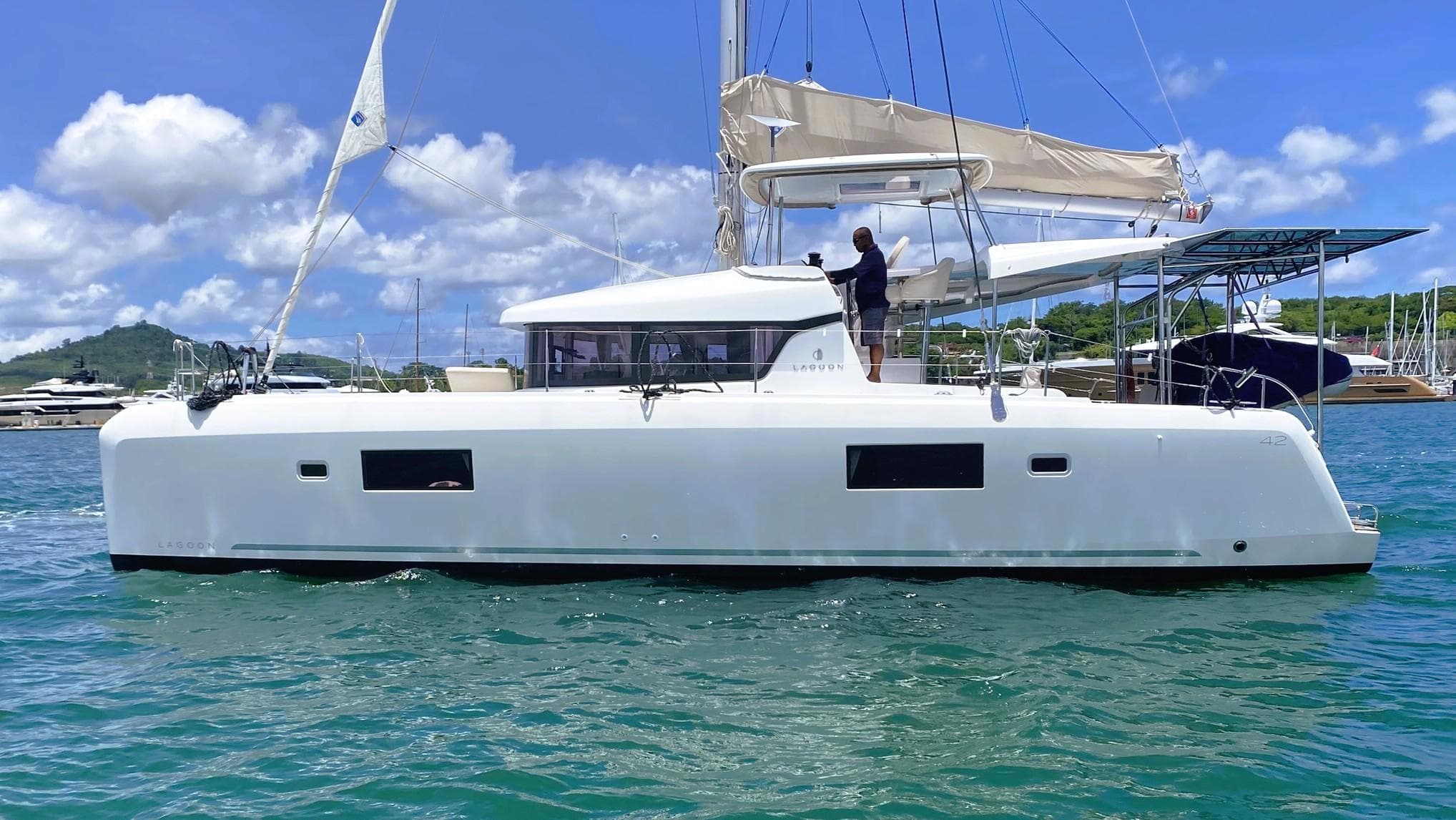2021 Lagoon 42 catamaran sailing on clear blue water under a sunny sky.