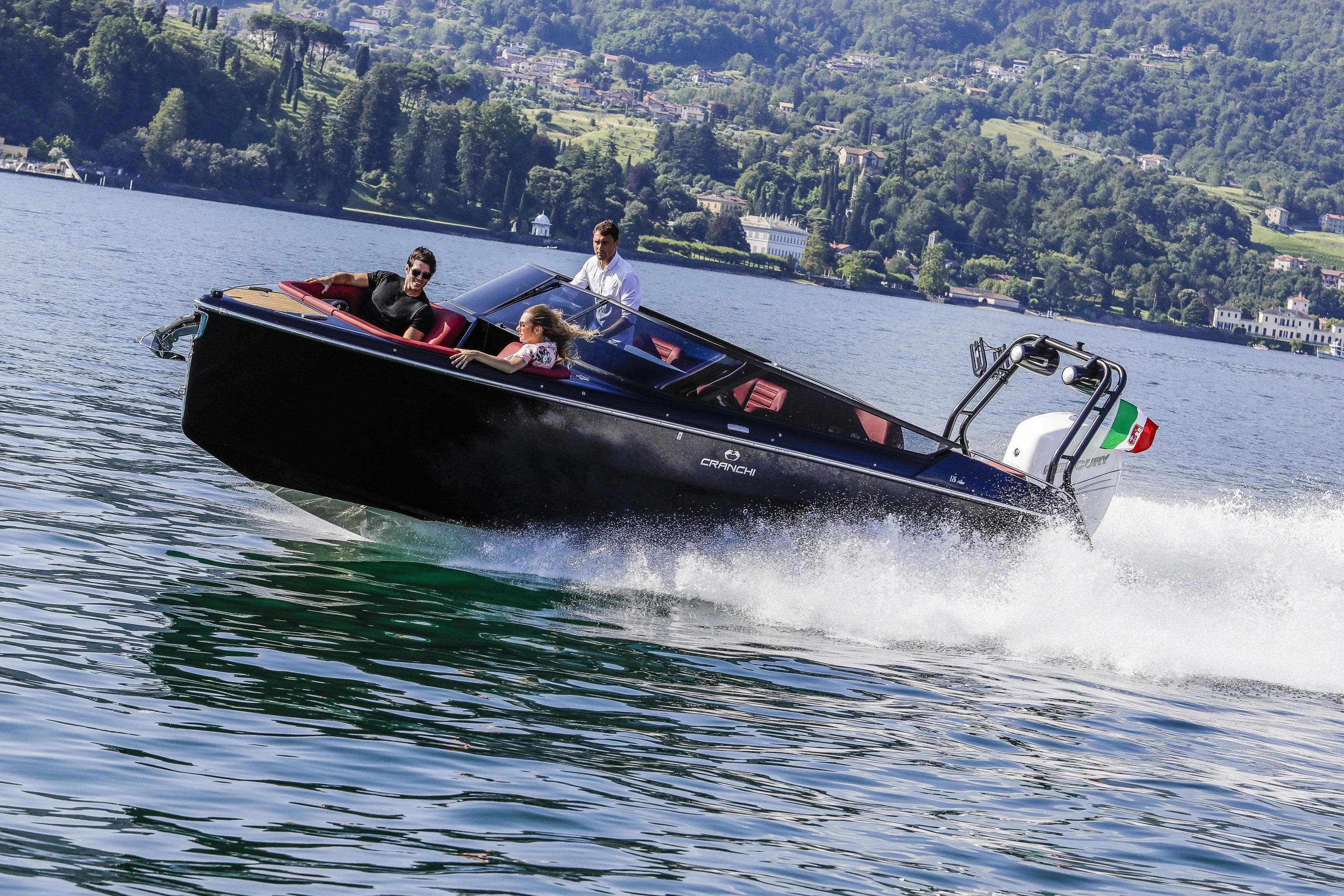 2026 Cranchi E26 Rider speedboat cruising on a scenic lake with passengers.