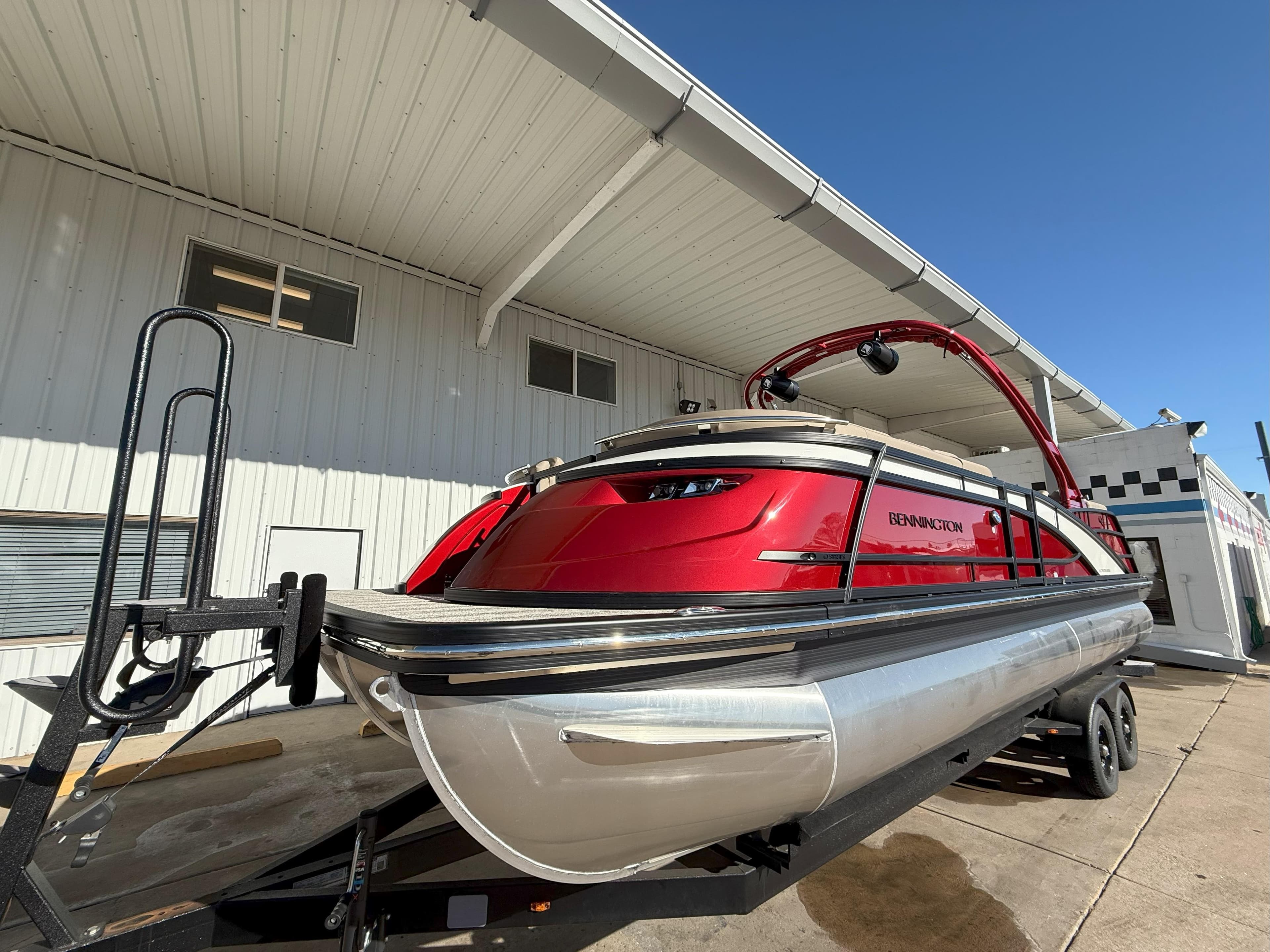 2025 Bennington 25QXFB pontoon boat in vibrant red, parked on a trailer.