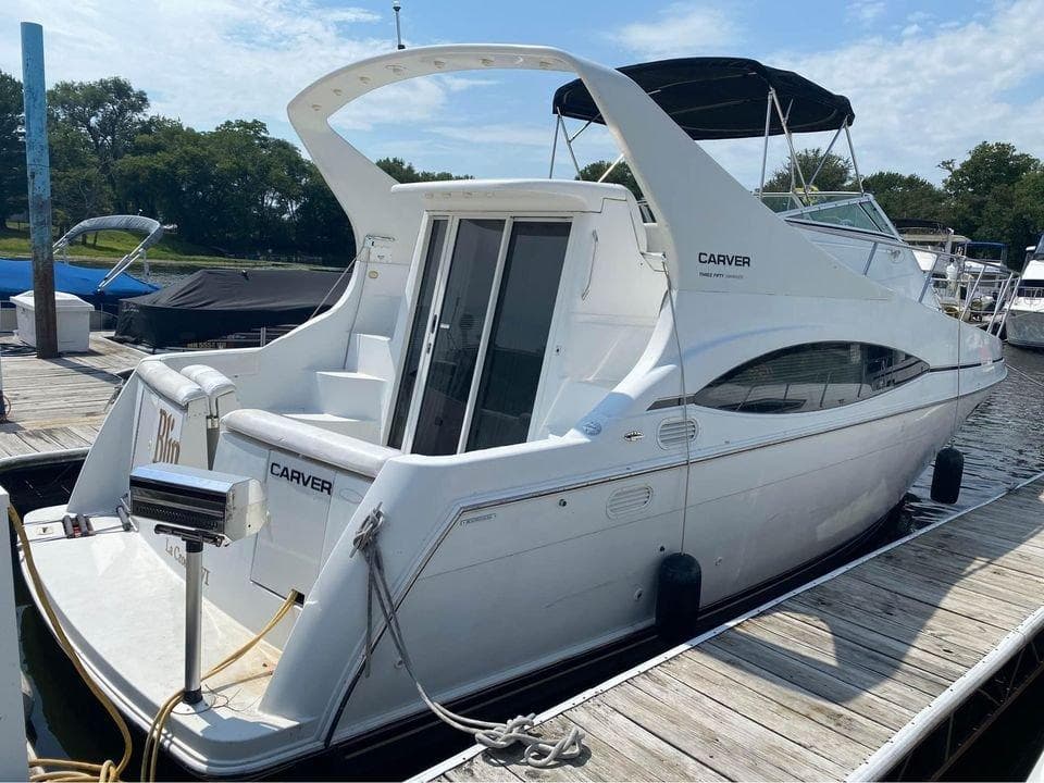 1999 Carver 350 Mariner yacht docked at marina, featuring sleek white design and spacious deck.