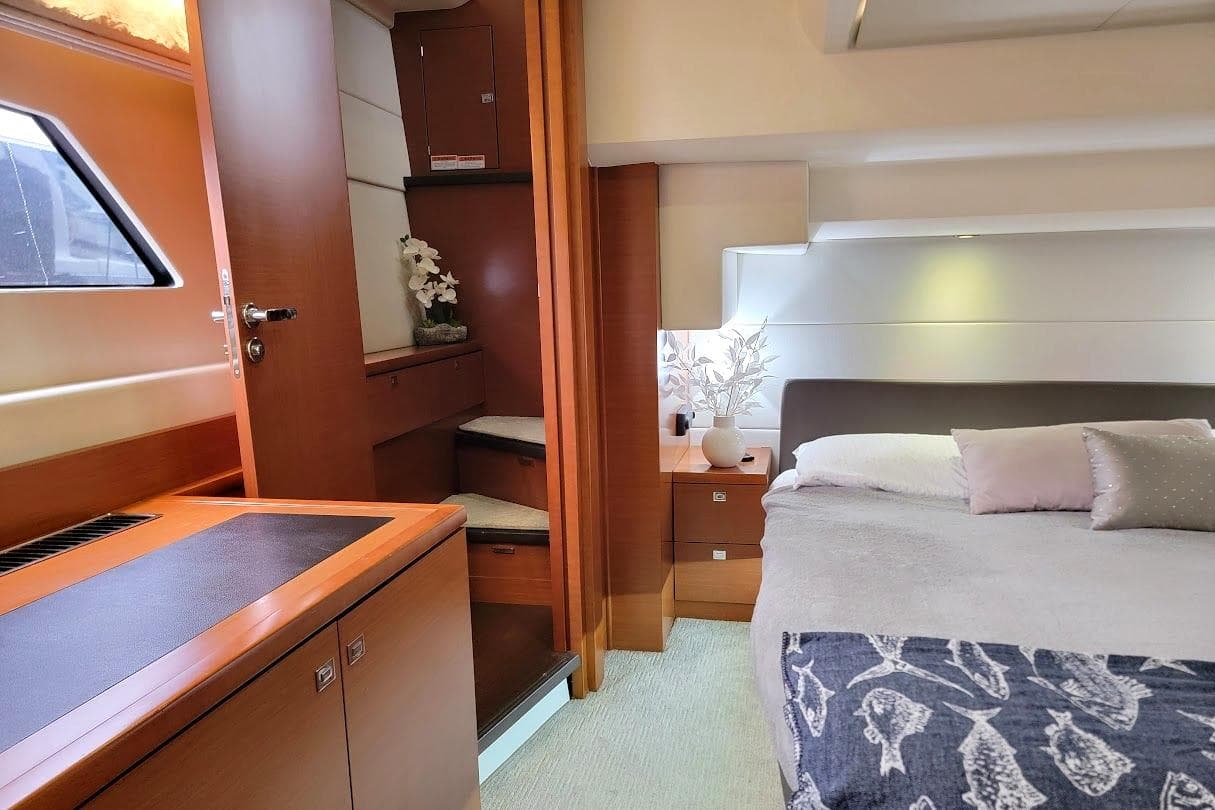 Luxurious 2014 Prestige 550 yacht interior with elegant bedroom and wooden cabinetry.
