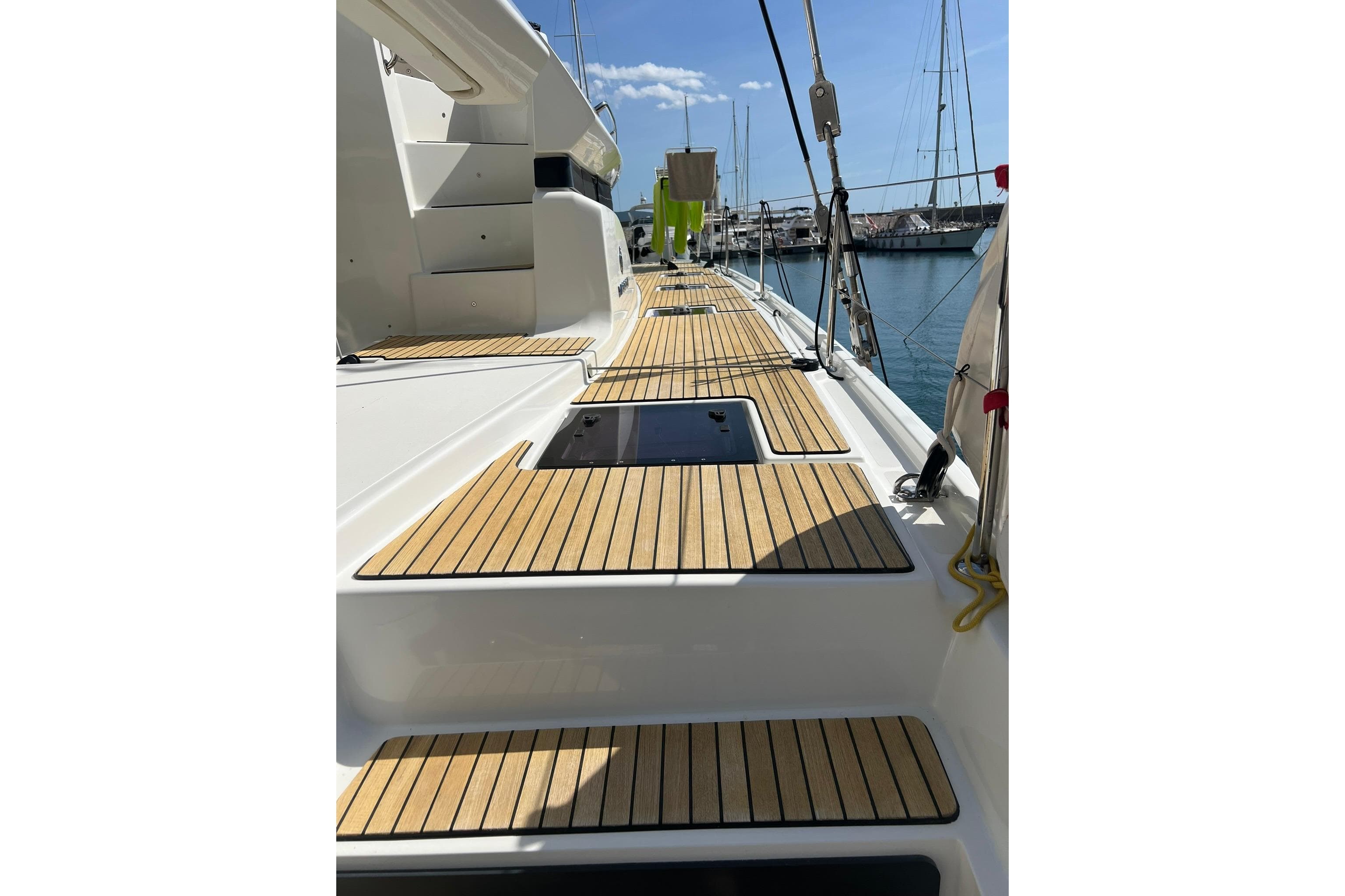 2020 Lagoon 50 yacht deck with wooden flooring, docked at marina under clear sky.